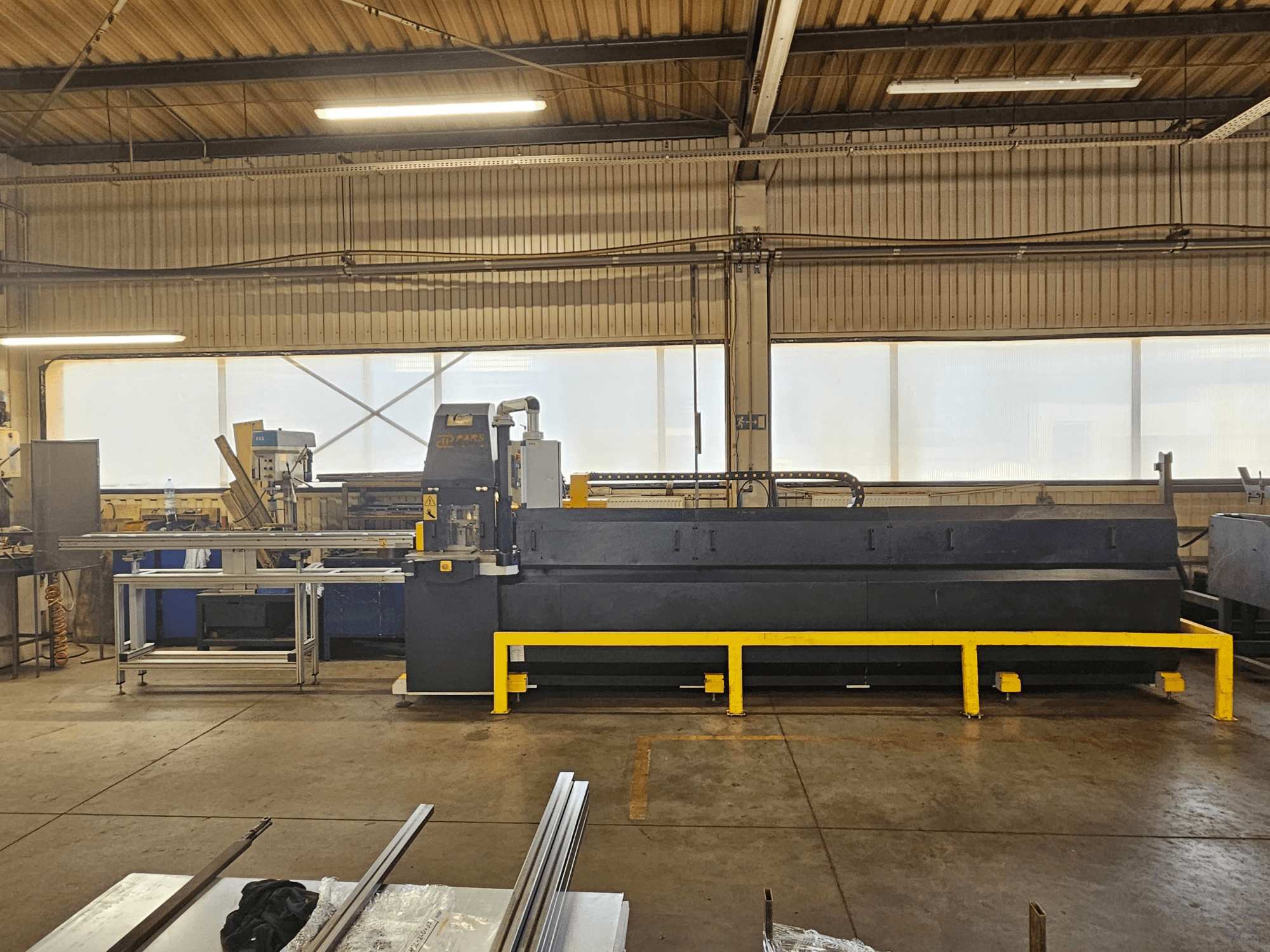 CNC-stantsimismasin PARS HMP SIRIUS PLUS-3000/3-L1, vaade eest tööstuslikus keskkonnas, kus on näha metallpinda ja tööriistu.