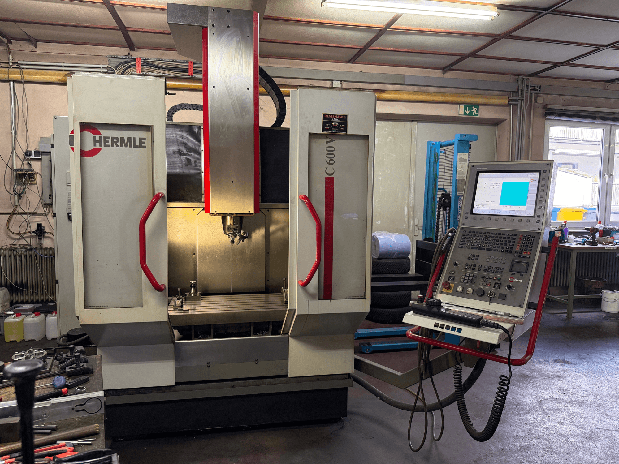 Hermle C 600 CNC-freesping eesvaates, millel on arvukate nuppudega juhtpaneel ja avar tööpind.