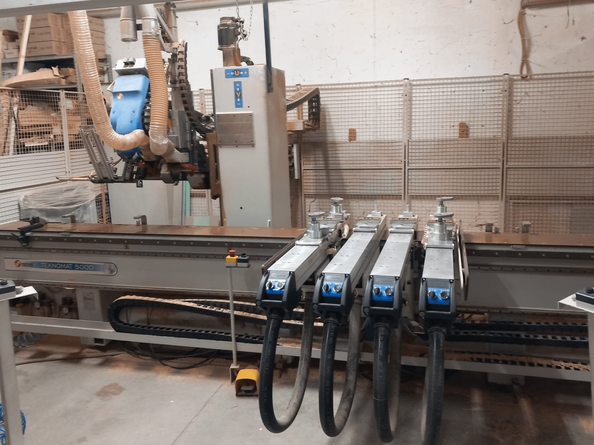 CNC-puidutöötluskeskus MASTERWOOD TEKNOMAT 5000, esivaade, millel on näha tööriistapea ja mitu imivoolikut.