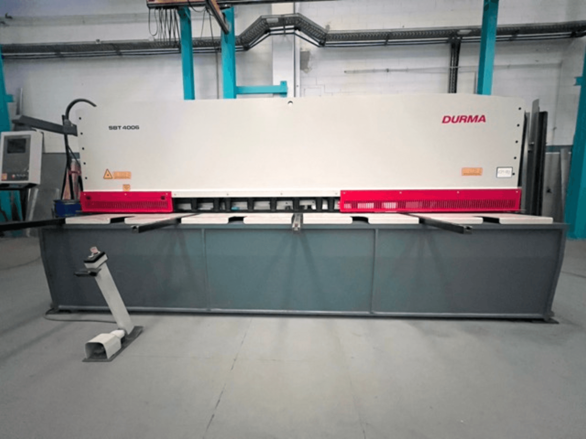 CNC lõikepink Durma SBT 4006 esiplaanil, millel on hall alus ja punased aktsendid, valmis tööks tehases.