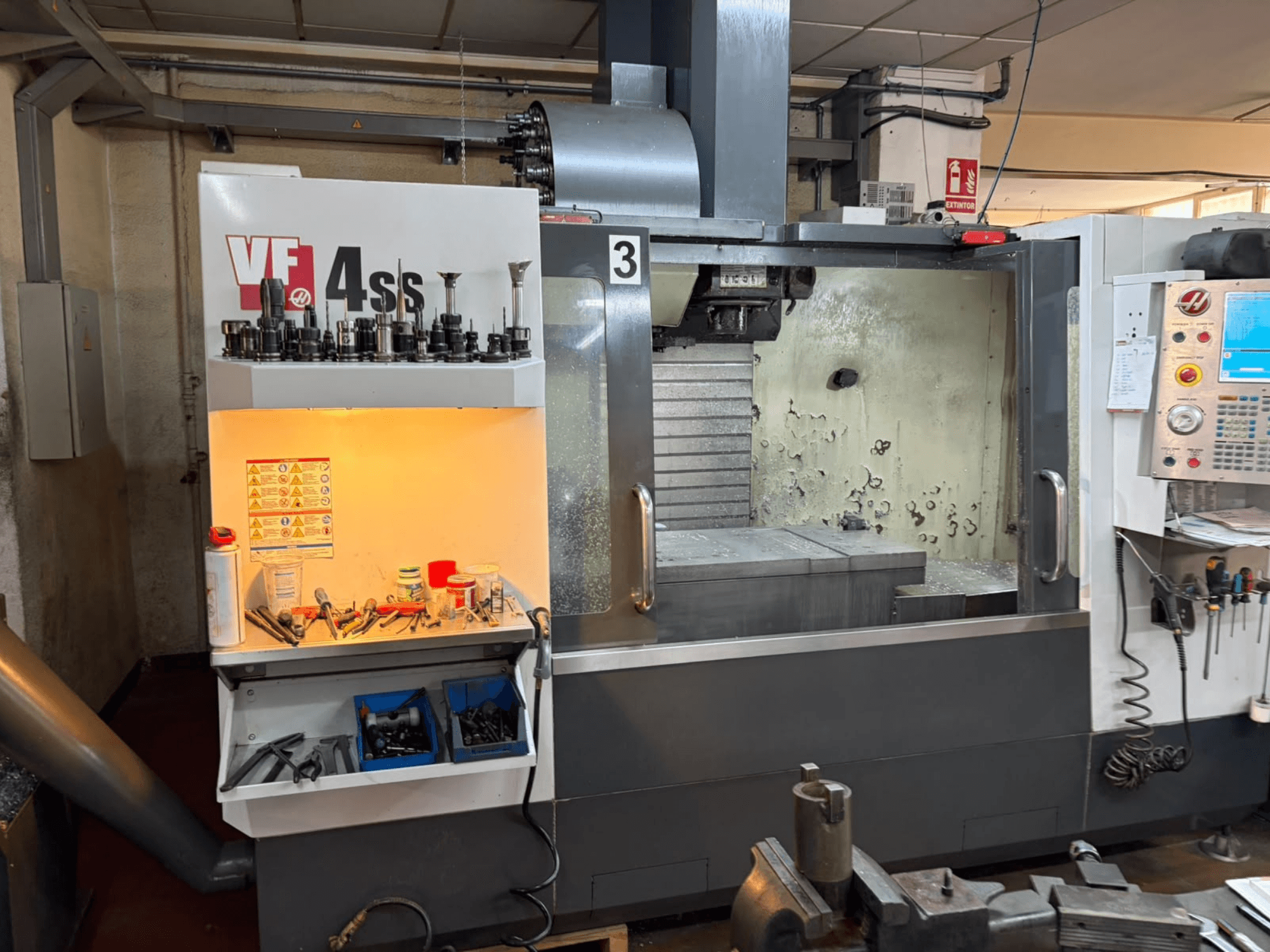 HAAS VP 4SS vertikaalne töötlemiskeskus, vaade eest, millel on näha tööriistade hoiuruum, juhtpaneel ja töötlemisdetailidega töötlemisala.