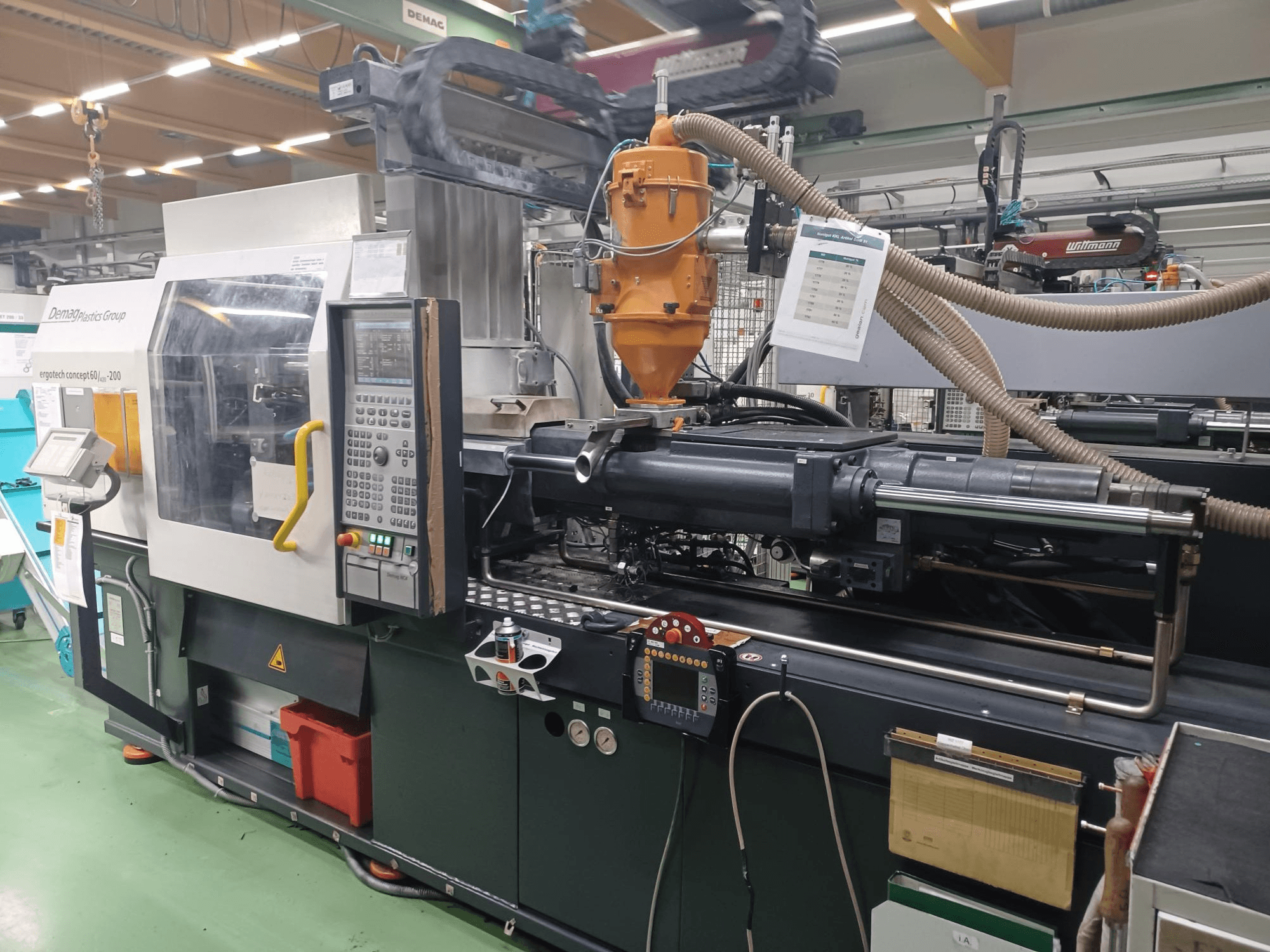 Demag Ergotech 200 survevalu masin, esiplaanil, juhtpaneel, pihusti ja töökomponendid nähtavad.