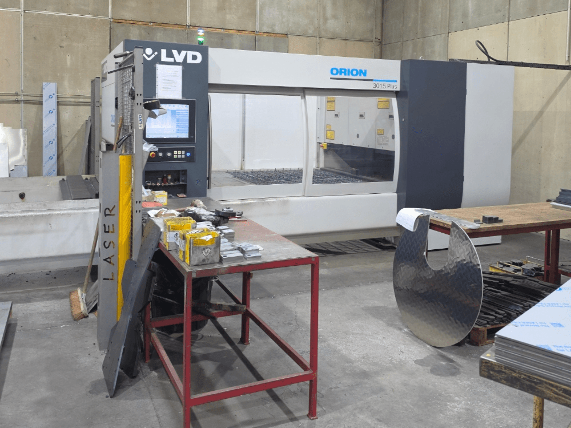 LVD Orion 3015 Plus CO₂-laserlõikepink, vaade eest koos juhtpaneeliga; tööpinnal on seda ümbritsevad metallosad.