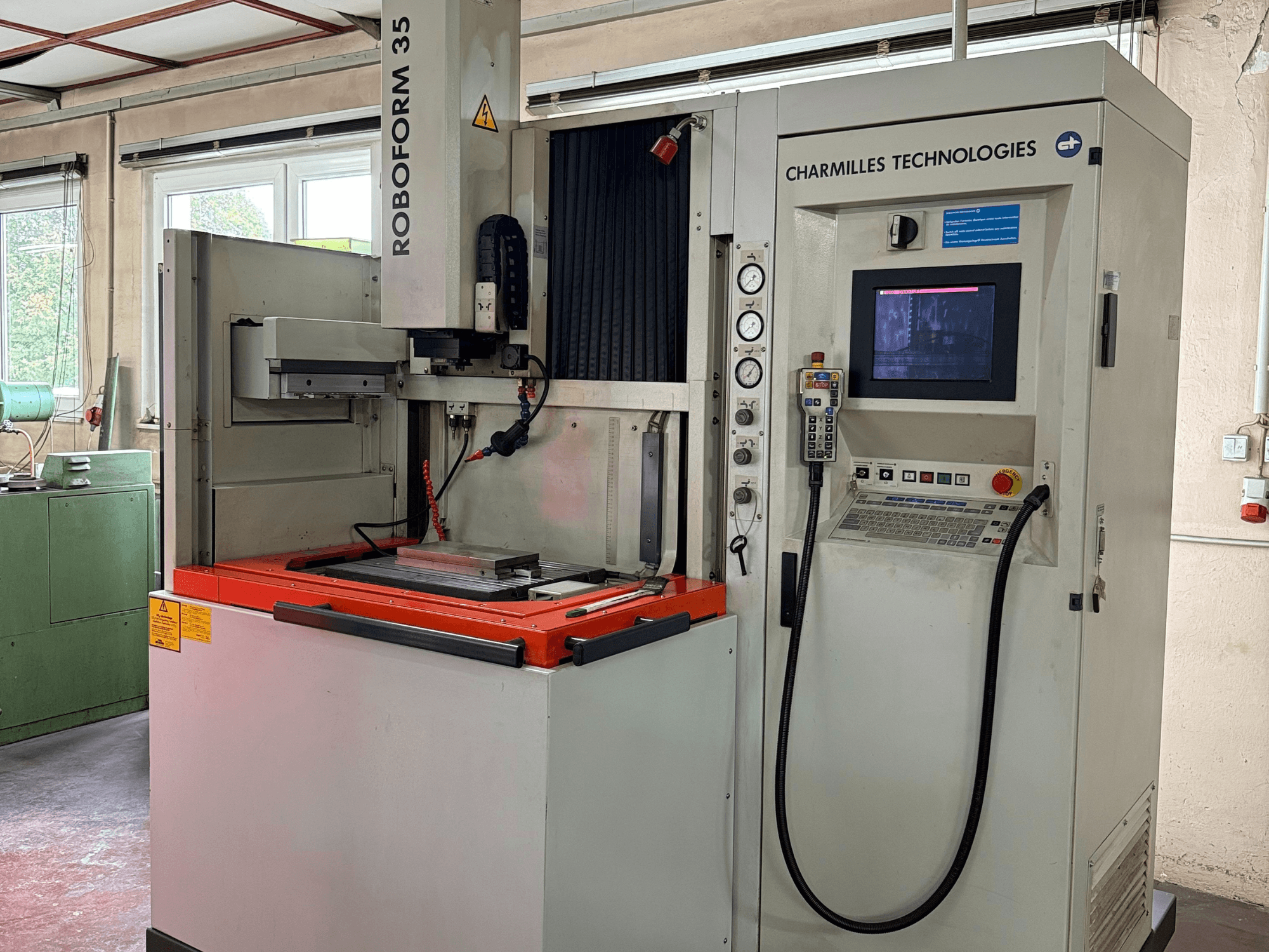 Charmilles Technologies Roboforn 35 masin, esiplaan, kus on näidatud juhtpaneel, paigaldatud tööriistad ja ohutussildid.