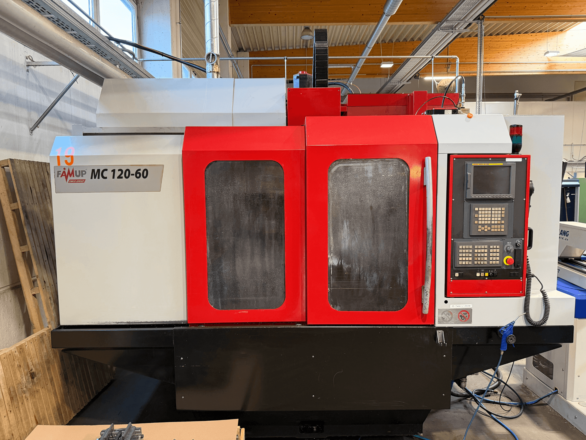 EMCO MC 120-60 vertikaaltöötluskeskuse esiplaan, millel on punane ja valge korpus, juhtpaneel ja kuvar.