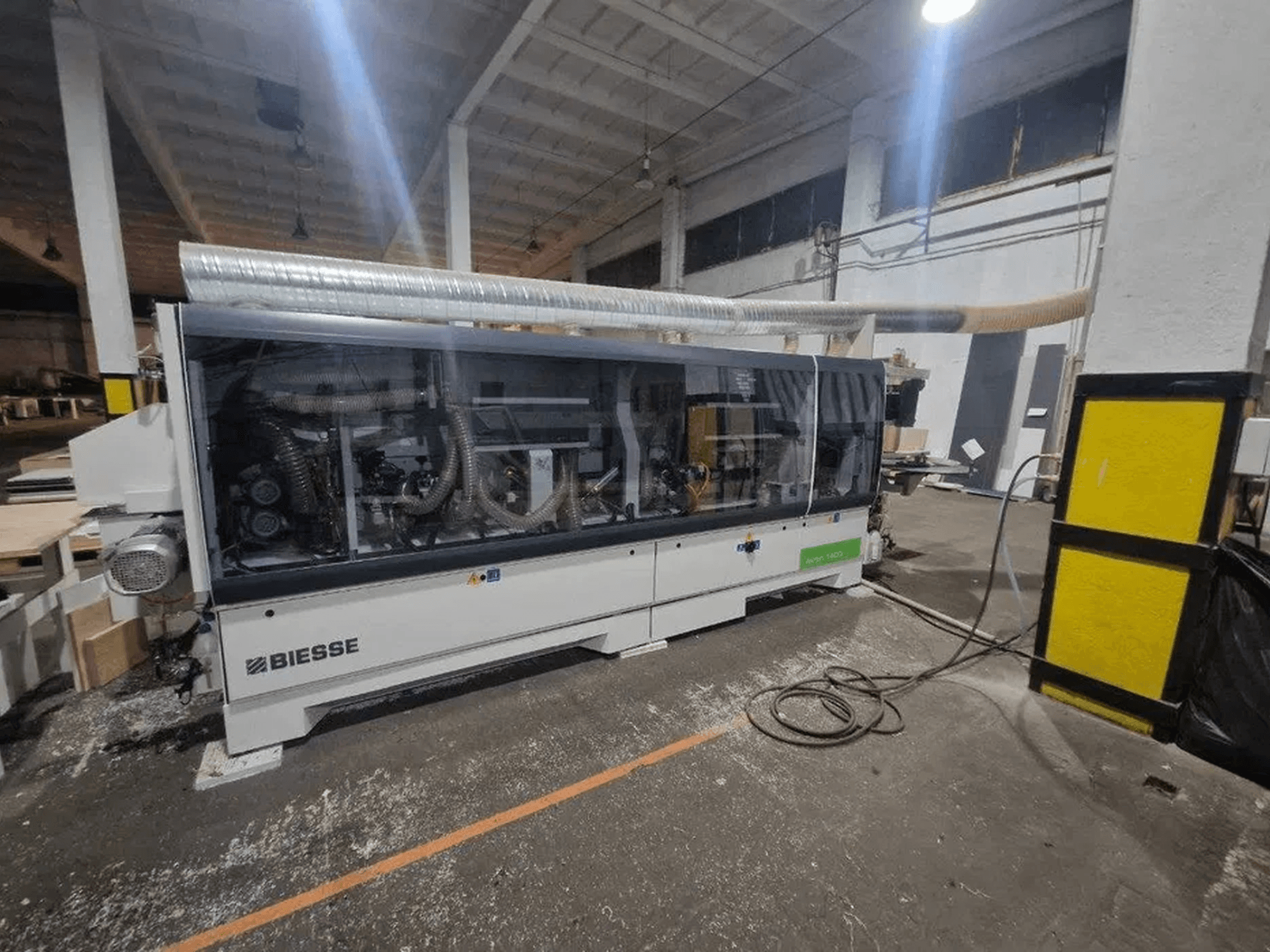 Töökojas asuv BIESSE Akron 1440 A servakleebimismasin, millel on läbipaistev kaitsekate ja nähtavad masinaosad.