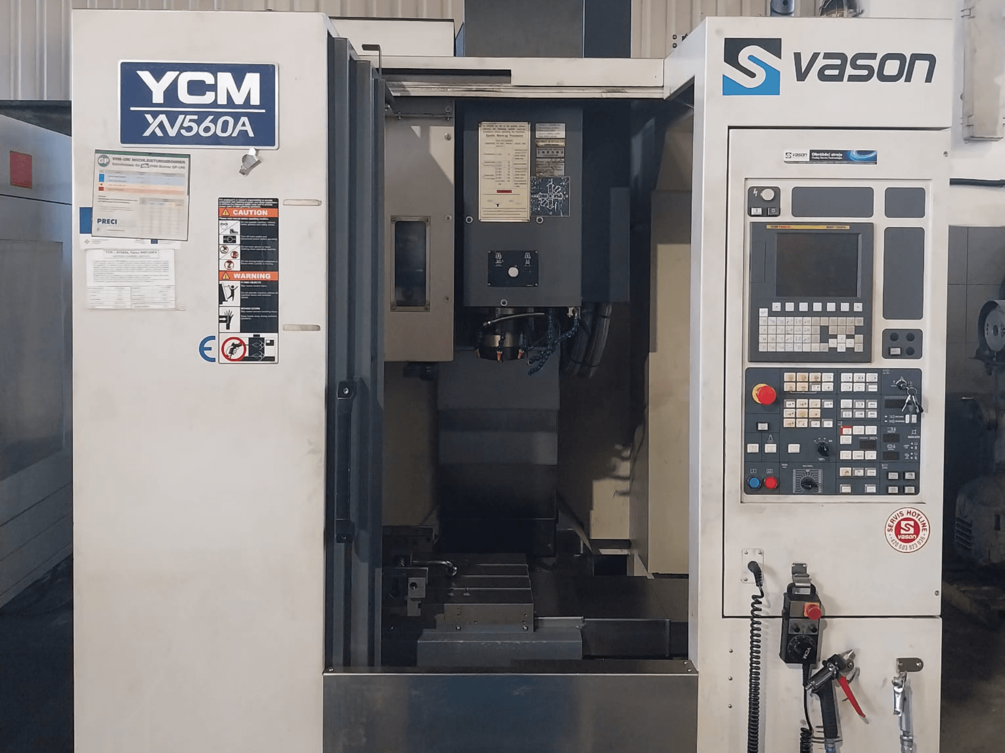 Püsttöötluskeskuse YCM XV 560A esiplaan, kus on näha juhtpaneel ja töölaud koos töötluskomponentidega.