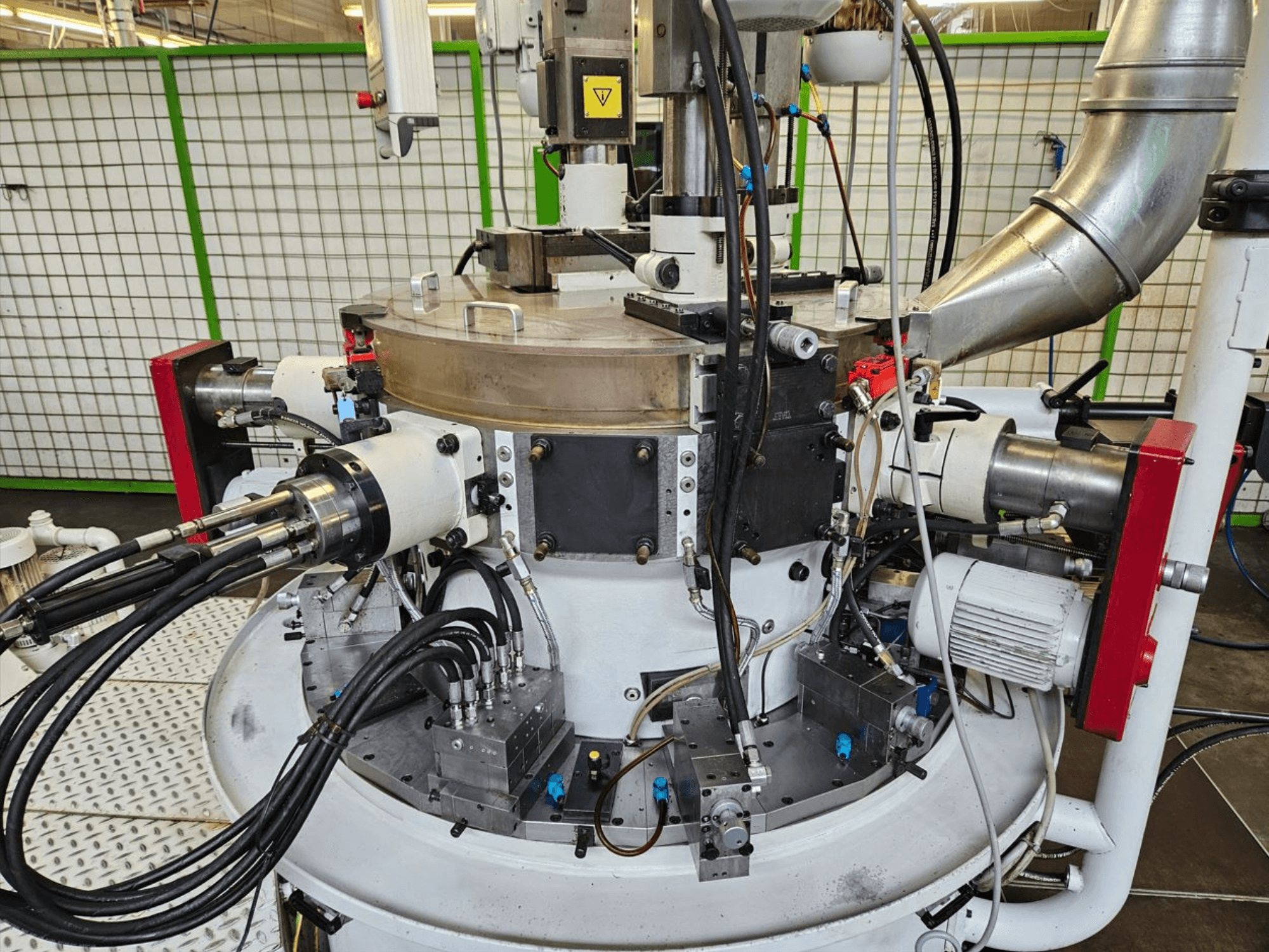 Lähivaade tööstuslikule masinale, millel on hüdraulilised voolikud, metallosad ja pöörlev alus. Marki ei ole näha.