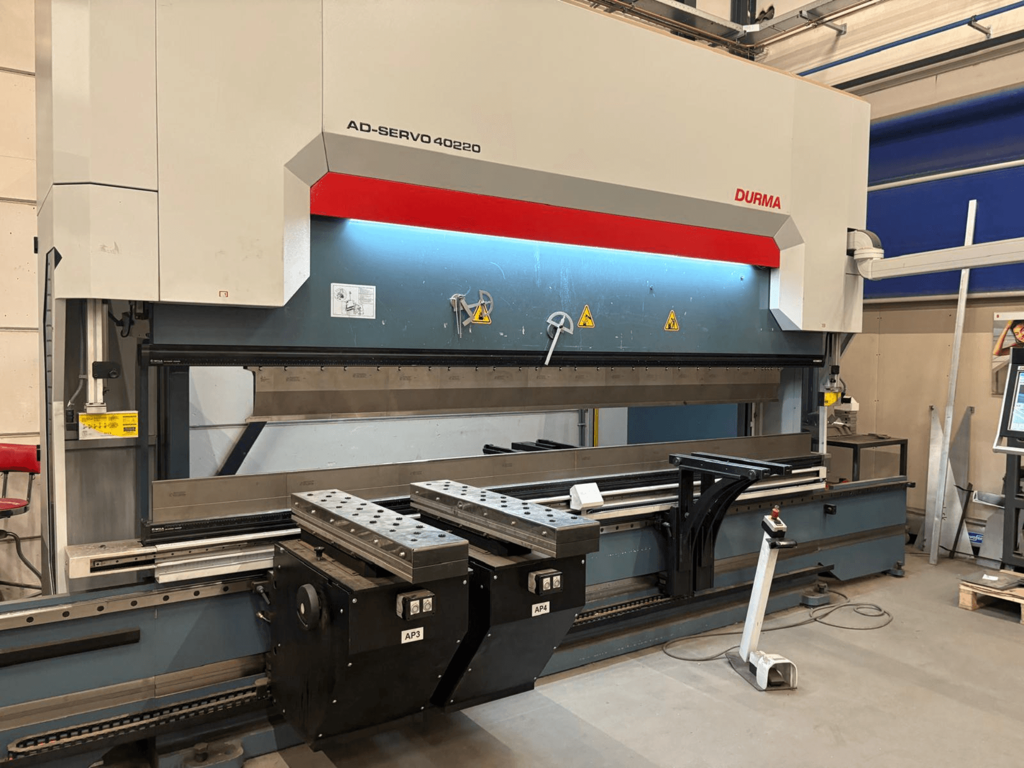 Durma AD-SERVO 40220 painutuspress, vaade eest, millel on näha juhtpaneel, hüdraulikasüsteem ja töölaual olevad tööriistad.