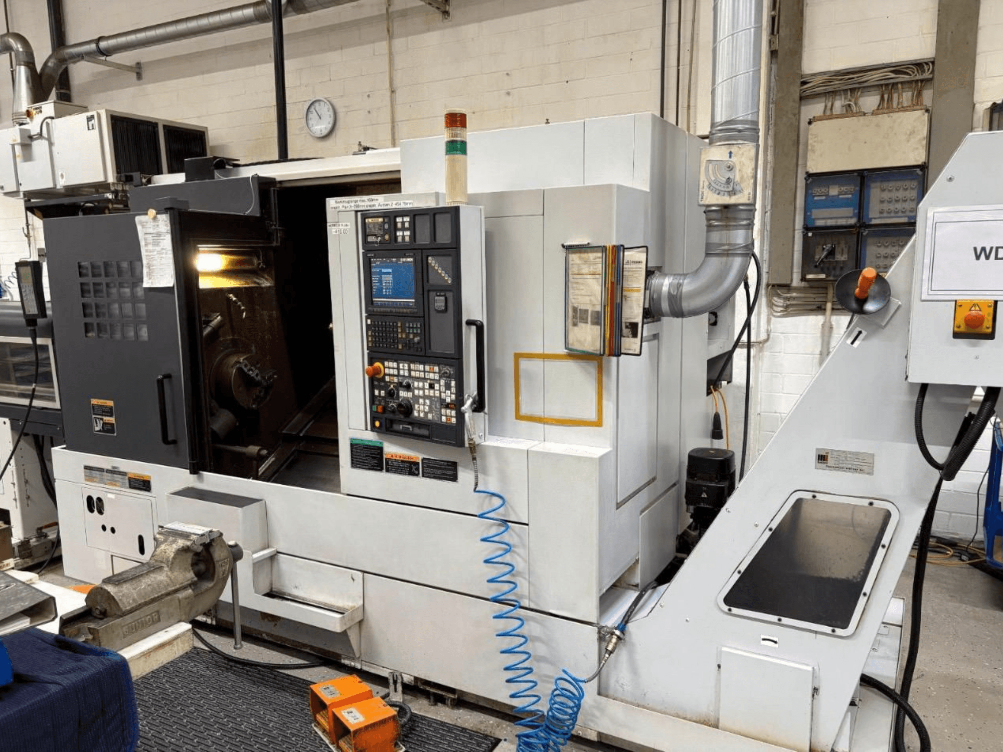 MORI SEIKI NL 2500 SY treipingikeskuse esiplaan, kus on näidatud juhtpaneel ja tööpiirkond. Nähtav jahutussüsteem ja tarvikud.