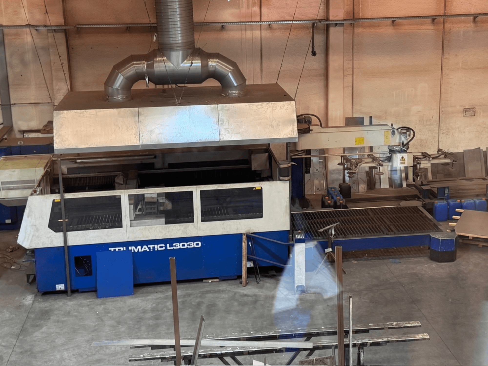 CO₂-laserlõikemasin TRUMPF TRUMATIC L3030 töökodas, vaade eest, millel on näha juhtpaneel ja lõikepind.