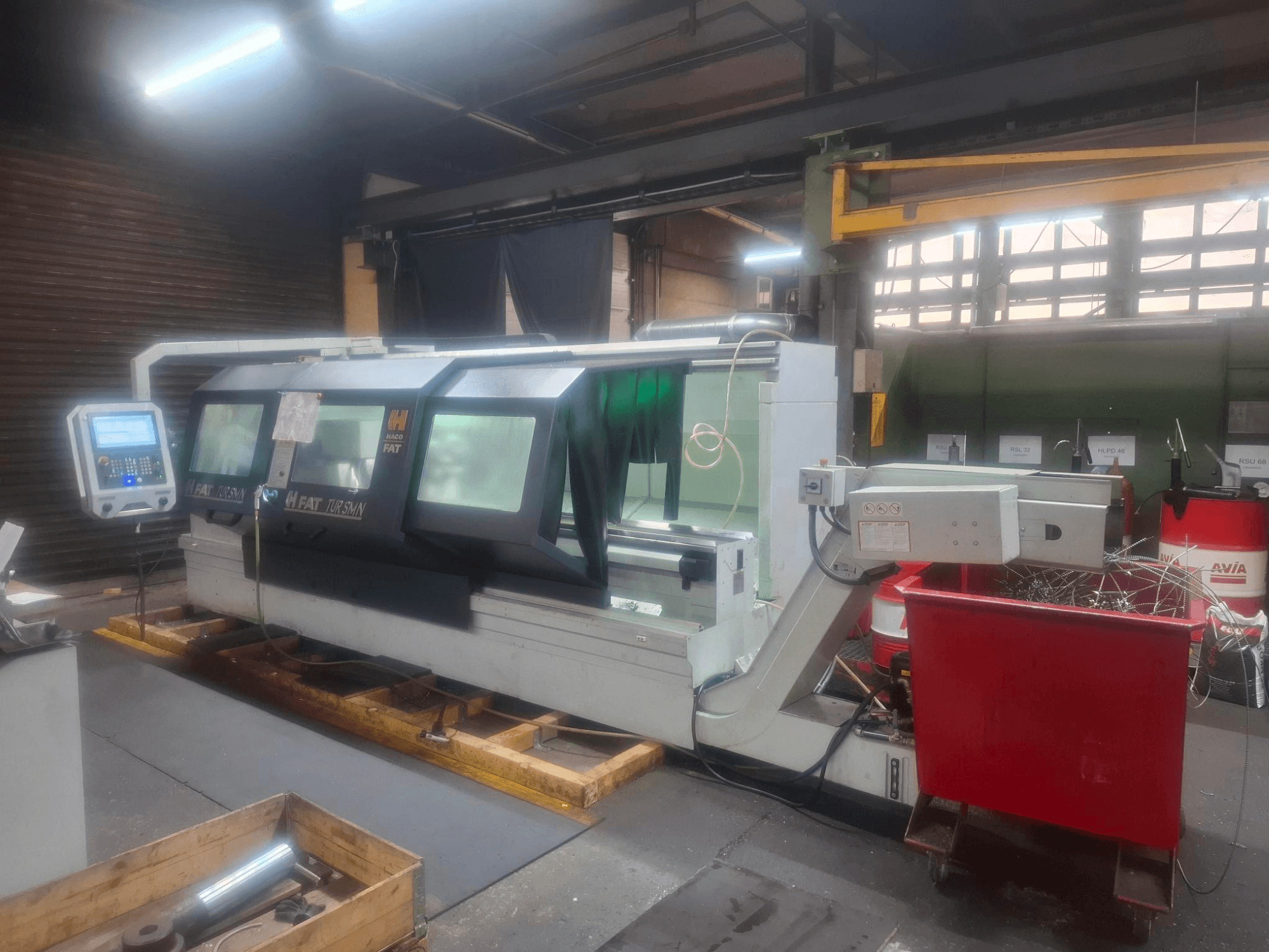 FAT Tursan CNC-tööpink koos juhtpaneeliga, mis on paigutatud puidust kaubaalustele töökojas.