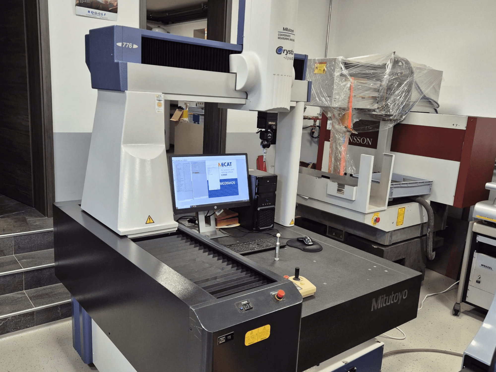 Mitutoyo mudel 776 koordinaatmõõtmismasin esiplaanil, ekraanil on nähtav mõõtmistarkvara ja juhtimisseadmed.