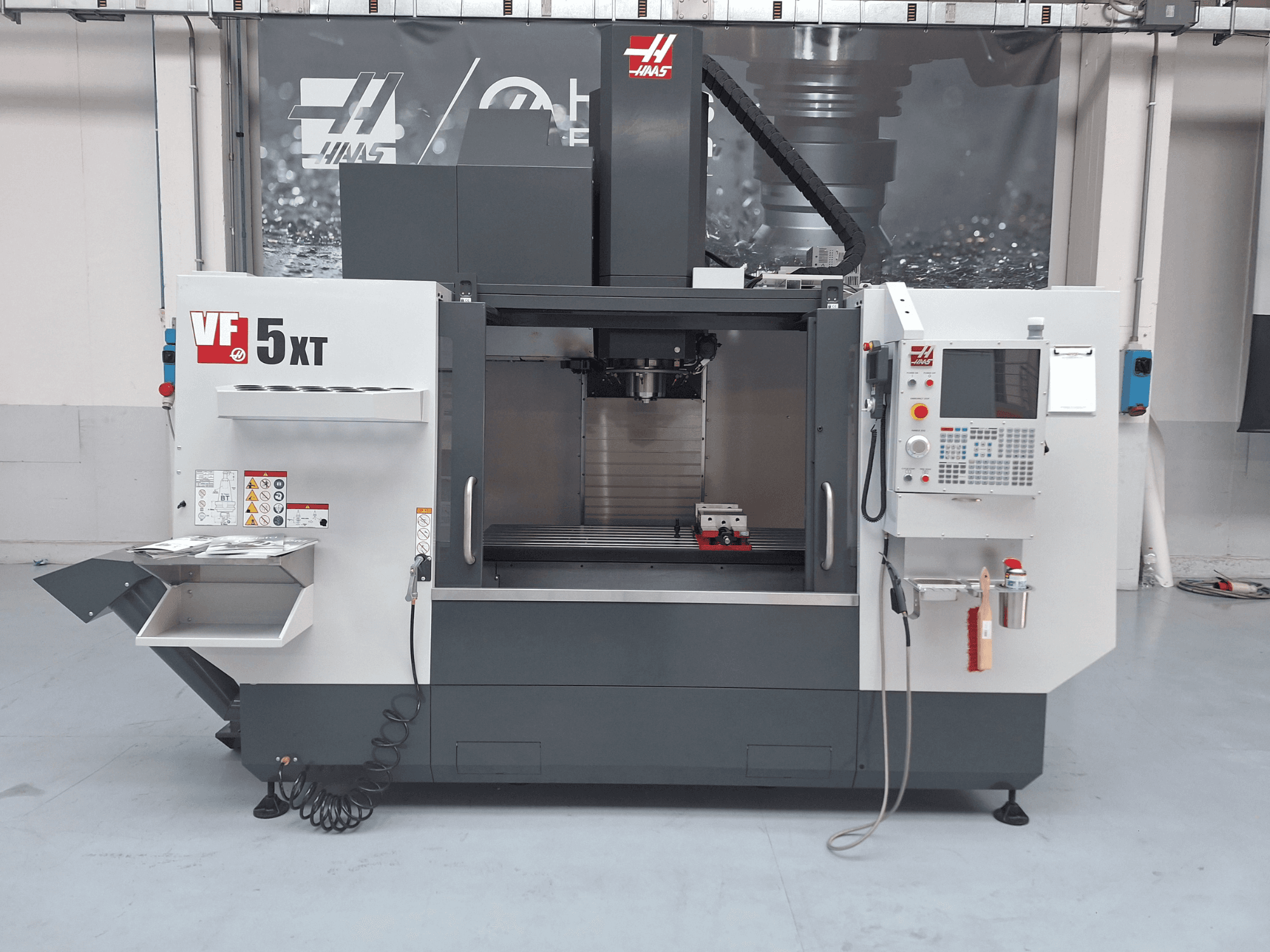 HAAS VF-5/50XT vertikaalne töötlemiskeskus, vaade eest, millel on näha juhtpaneel, spindli piirkond ja tööriistade hoiuruum.