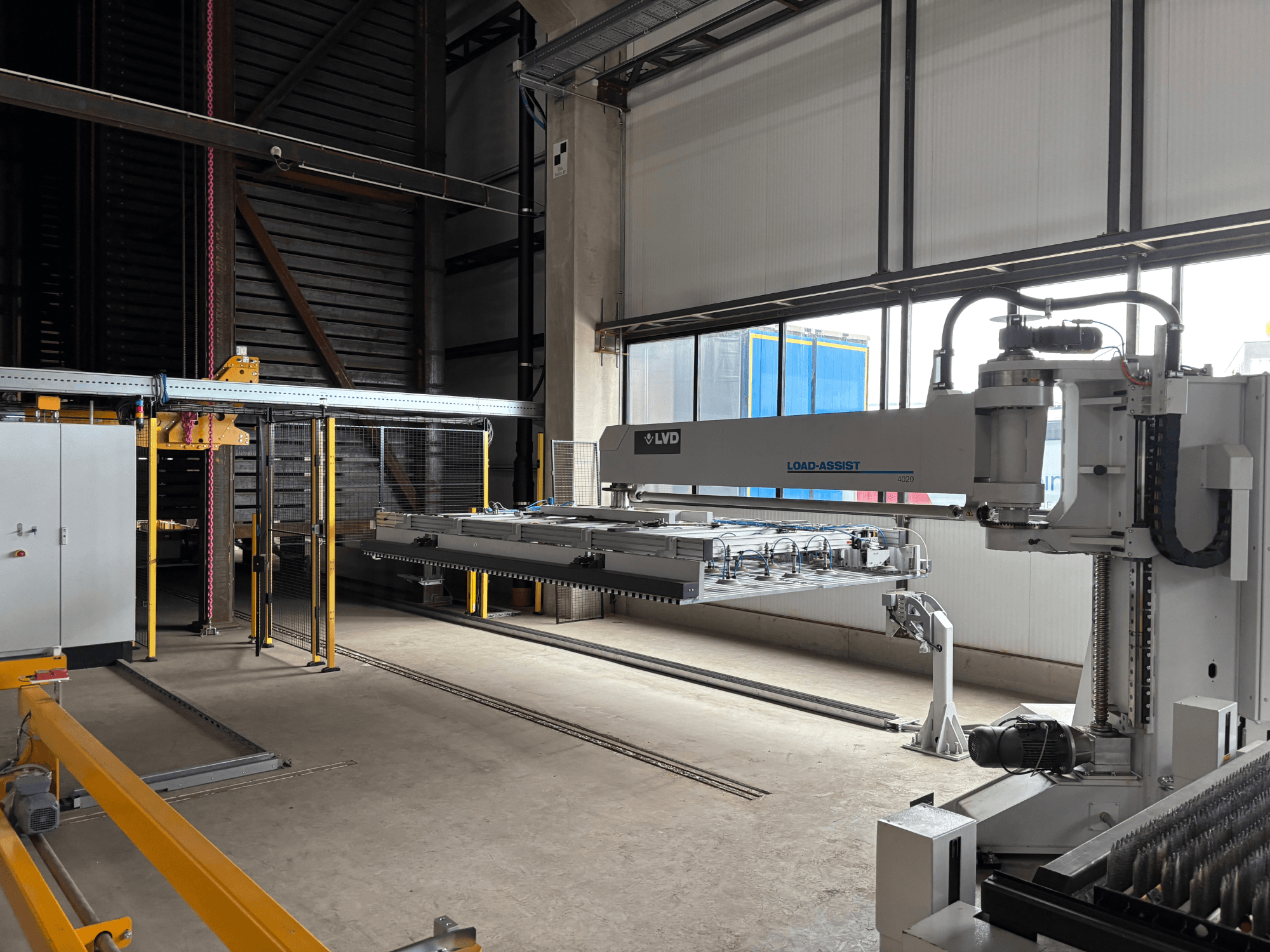 LVD Load-Assist 4020 automaatikaseadmed esiplaanil koos robotkäe ja laadimissüsteemiga, mis on nähtav suures tööruumis.