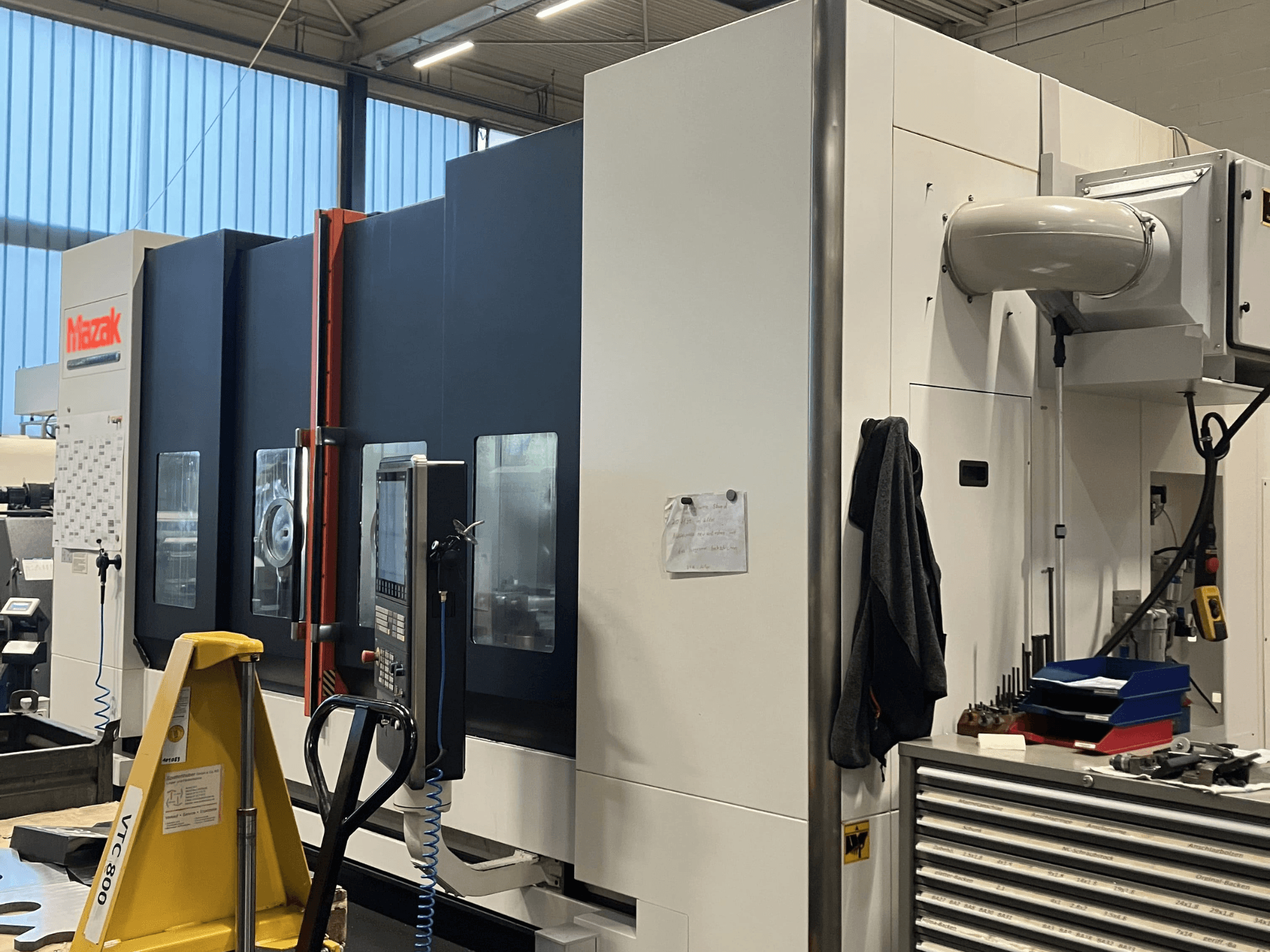 Mazaki CNC-tööpink, küljelt vaadatuna, kus näidatakse juhtpaneeli ja ohutusfunktsioone töökojas.