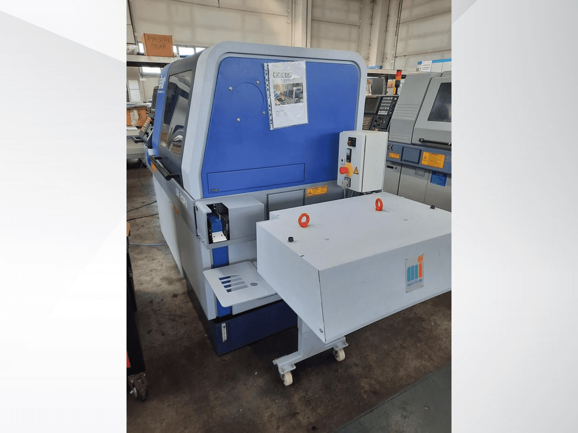 Sinine tööstuslik masin valge konveieriga, millel on näidatud juhtpaneel ja lisatud ohutusseadmed, külgvaade.