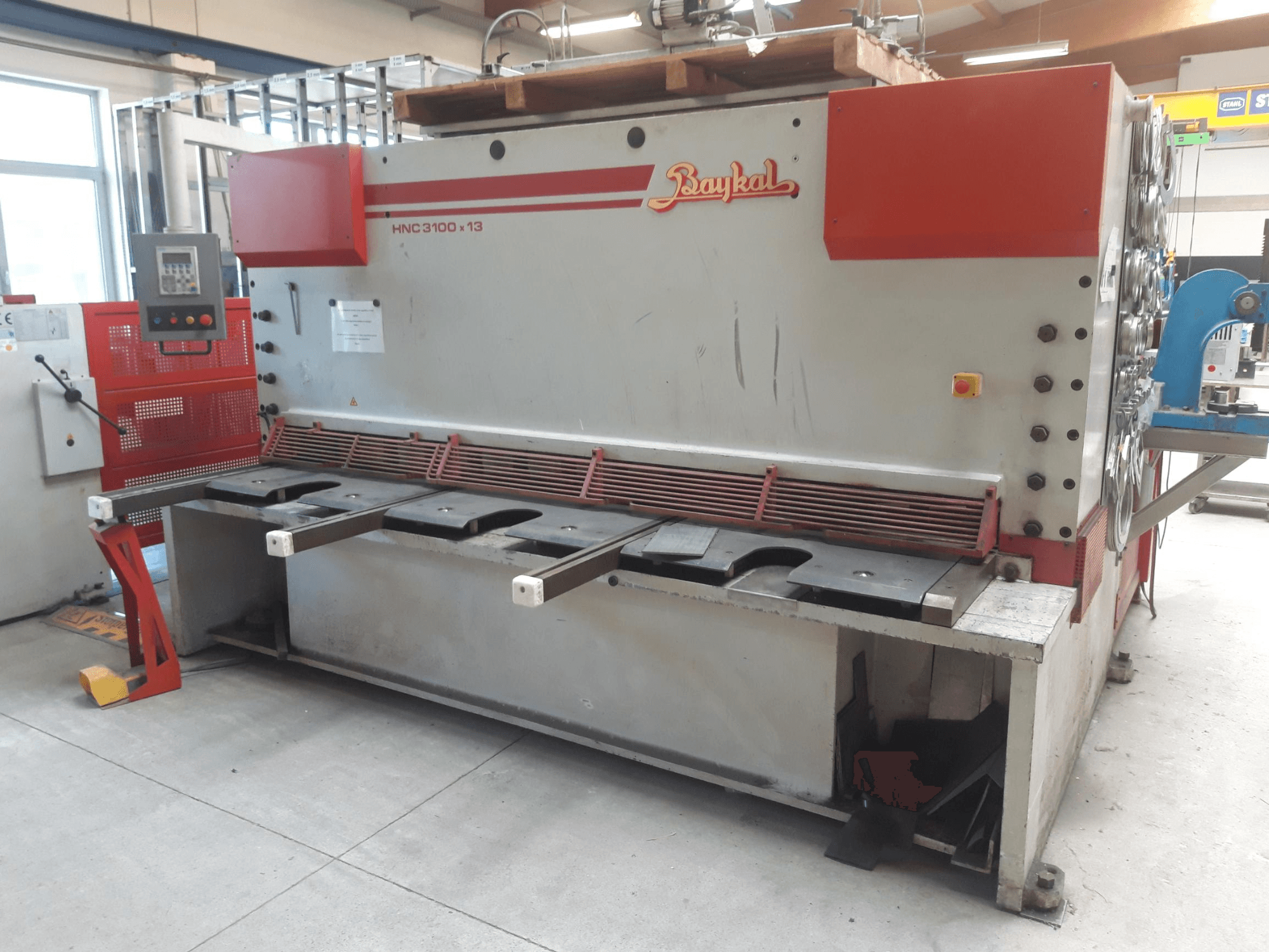 Baykal HNC 3100x13 CNC-lõikepingi esivaade, millel on juhtpaneel, metallilõikepind ja jäätmete kogumisruum.