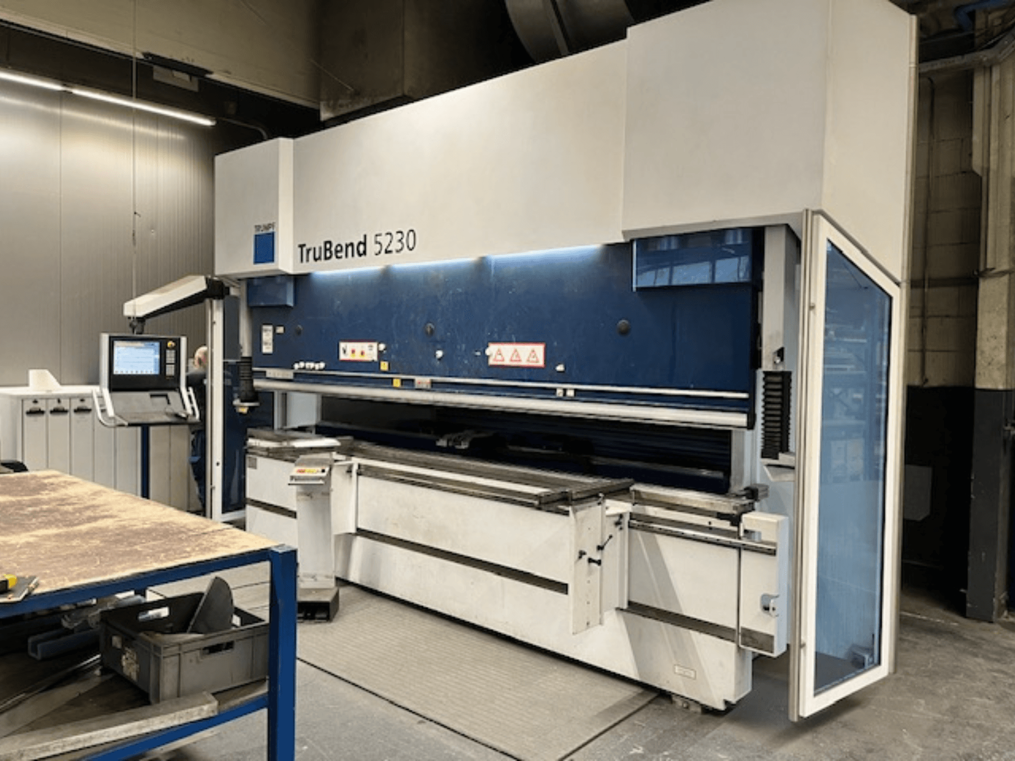 TruBend 5230 painutuspink tööstuslikus keskkonnas; esiplaanil on näidatud juhtpaneel, ohutusseadmed ja töölaud.