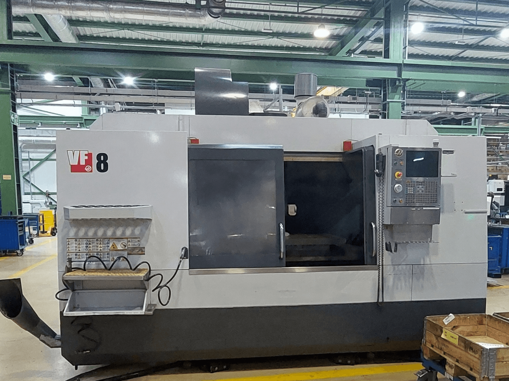 HAAS VF-8 vertikaalne töötlemiskeskus, vaade eest; varustatud juhtpaneeli ja laadimisalaga, mõeldud täpsete töötlemistoimingute teostamiseks.