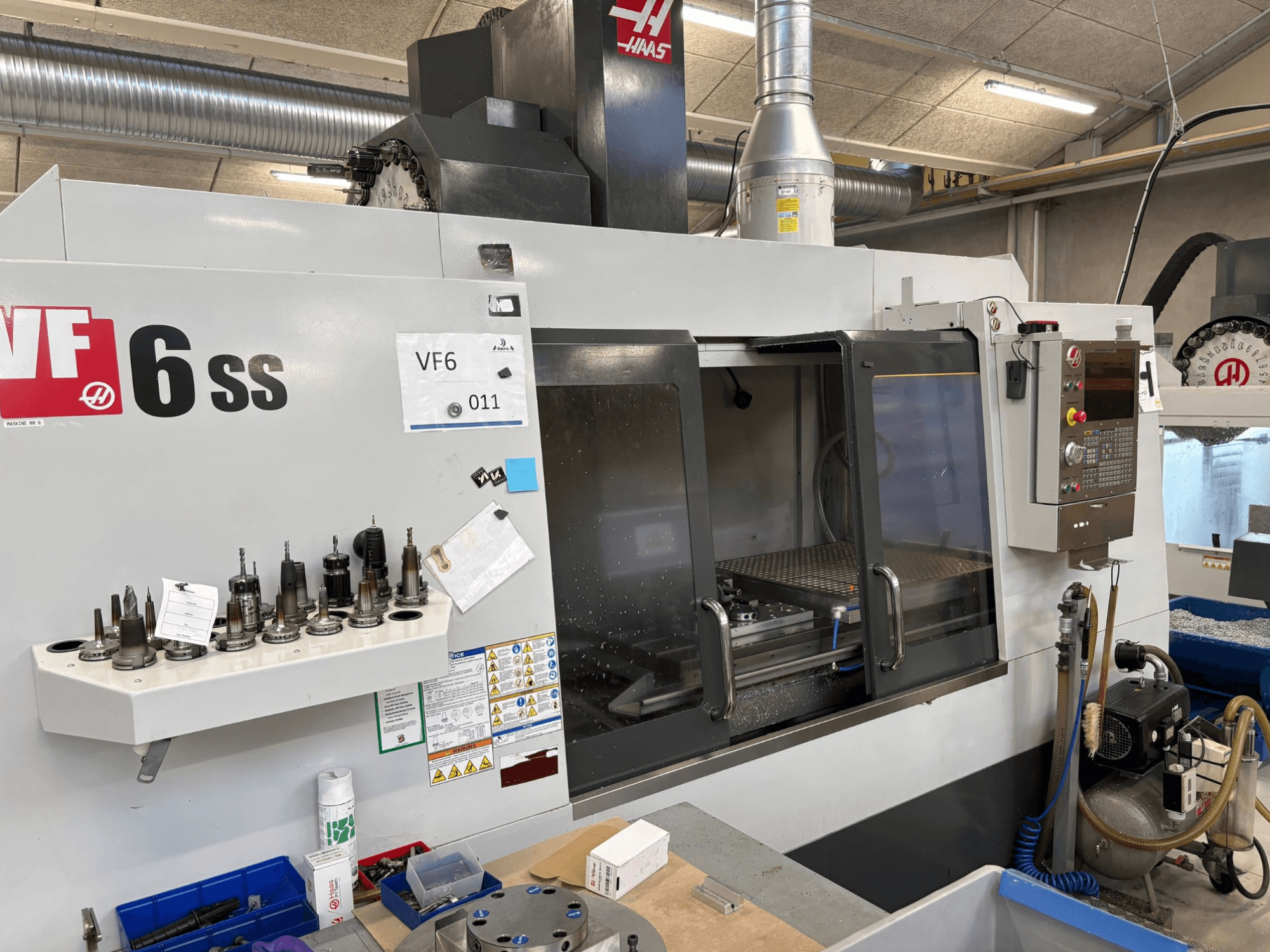 Haas VF-6 SS CNC-freesping, esiplaanil. Erinevad tööriistad, juhtpaneel ja nähtav sisemine tööruum.