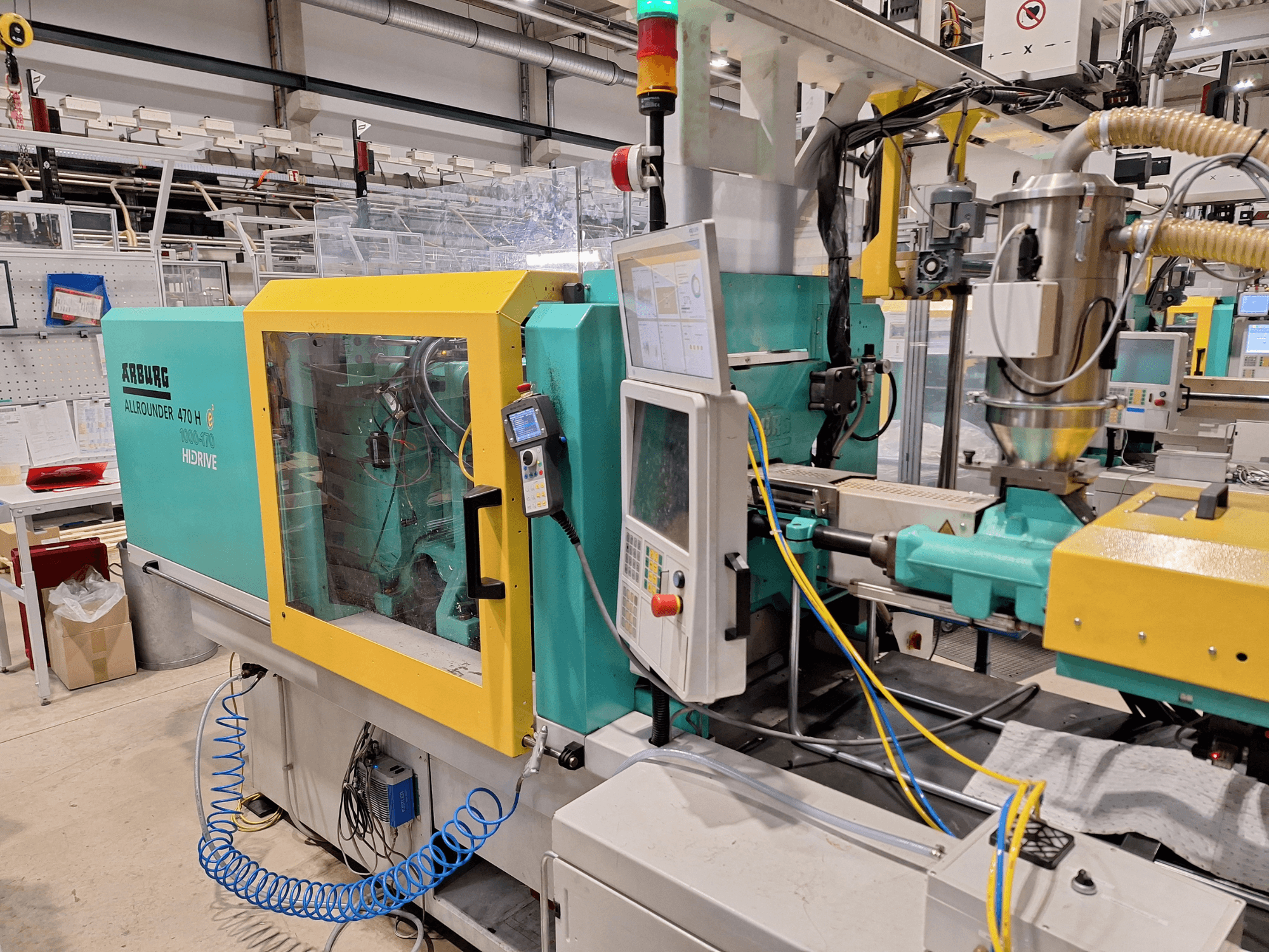 Arburg 470 H 1000-170 hüdrauliline survevalu masin, külgvaade juhtpaneelile ja söötmissüsteemile.