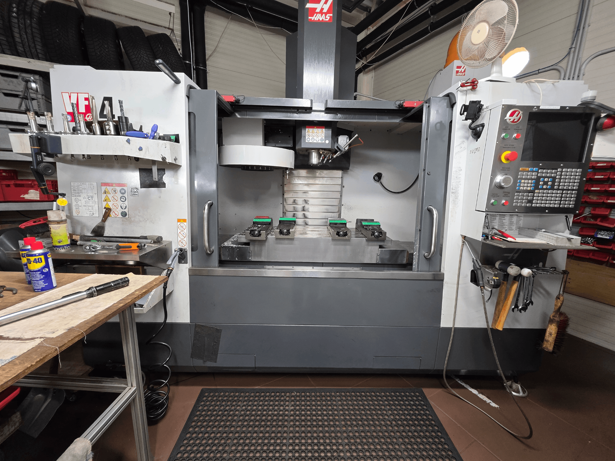Haas VF-4 CNC-veski esivaade töökojas, kus on tööriistad, arvutiliides ja kaks töödeldavat detaili laual.