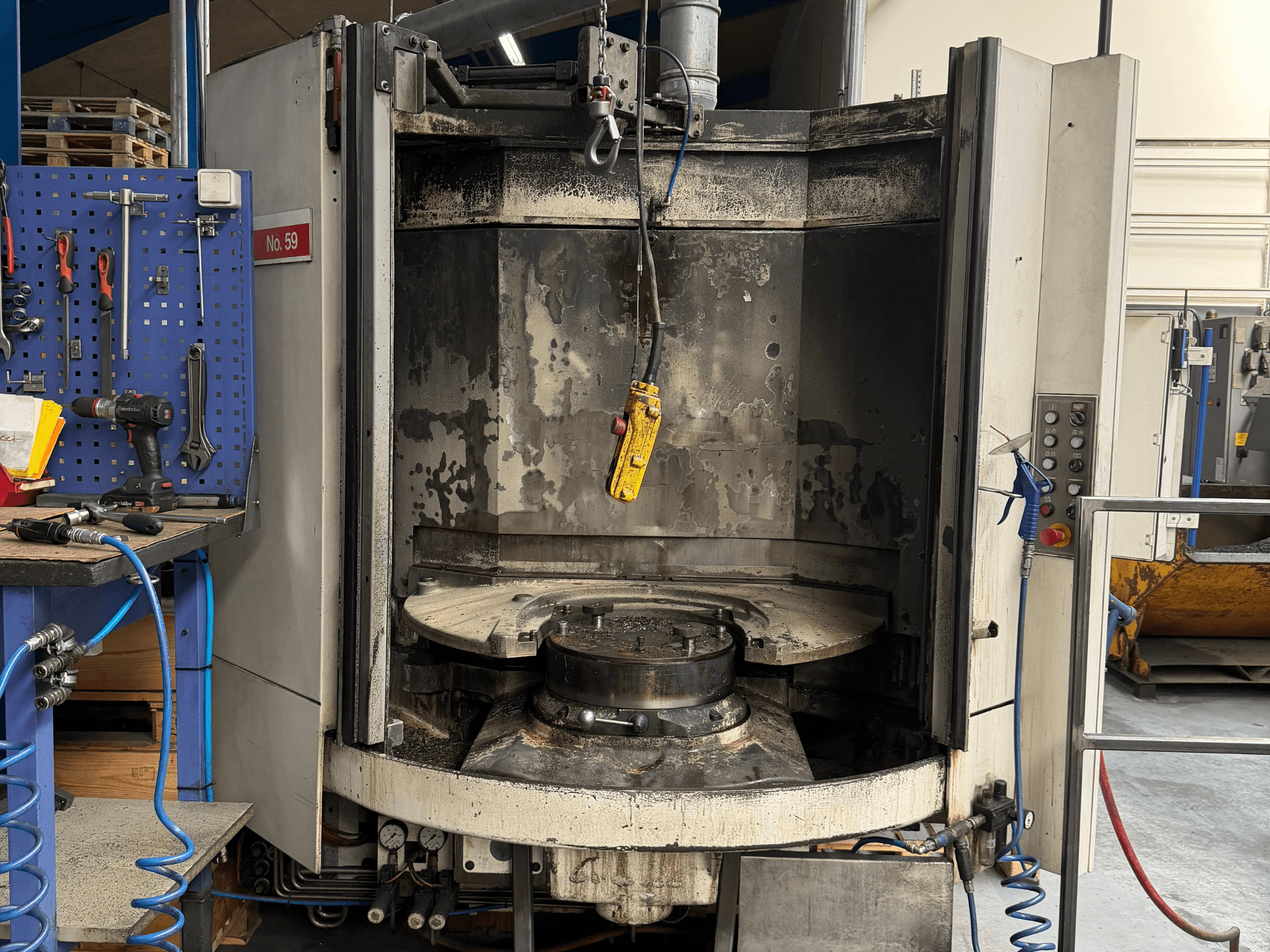 Horisontaalne töötlemiskeskus HELLER MC 16 esiplaanil, kus on näha tühi töölaud ja juhtpaneel, töökoja seadistuses.