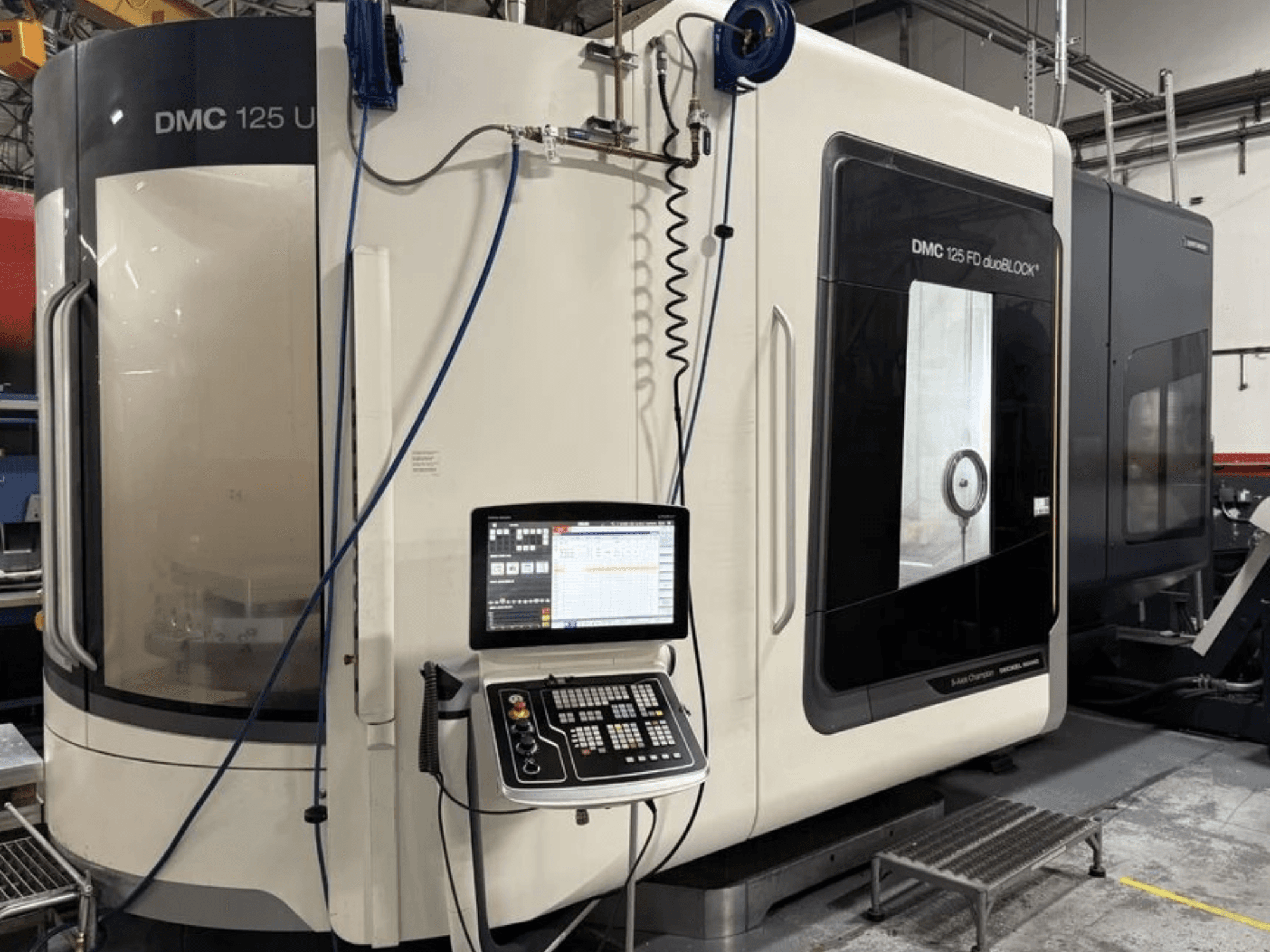 Universaalne töötlemiskeskus DMG MORI DMC 125 U duoBLOCK, vaade eest, kus on näha juhtpaneel ja peegeldavad pinnad.