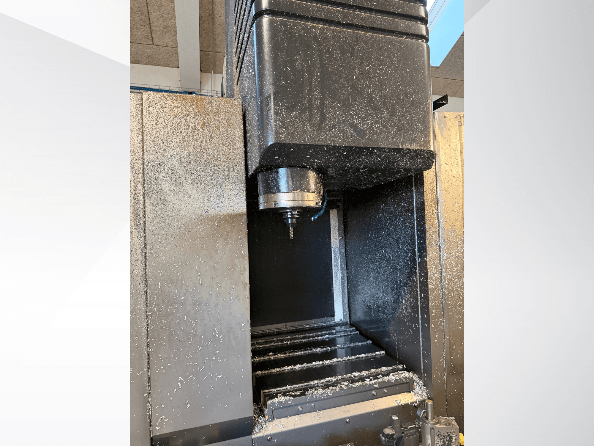 Mazak VTC 300C II vertikaalne töötlemiskeskus, vaade eest, millel on näha spindel ja töötlemisprotsessi käigus tekkinud laastud.