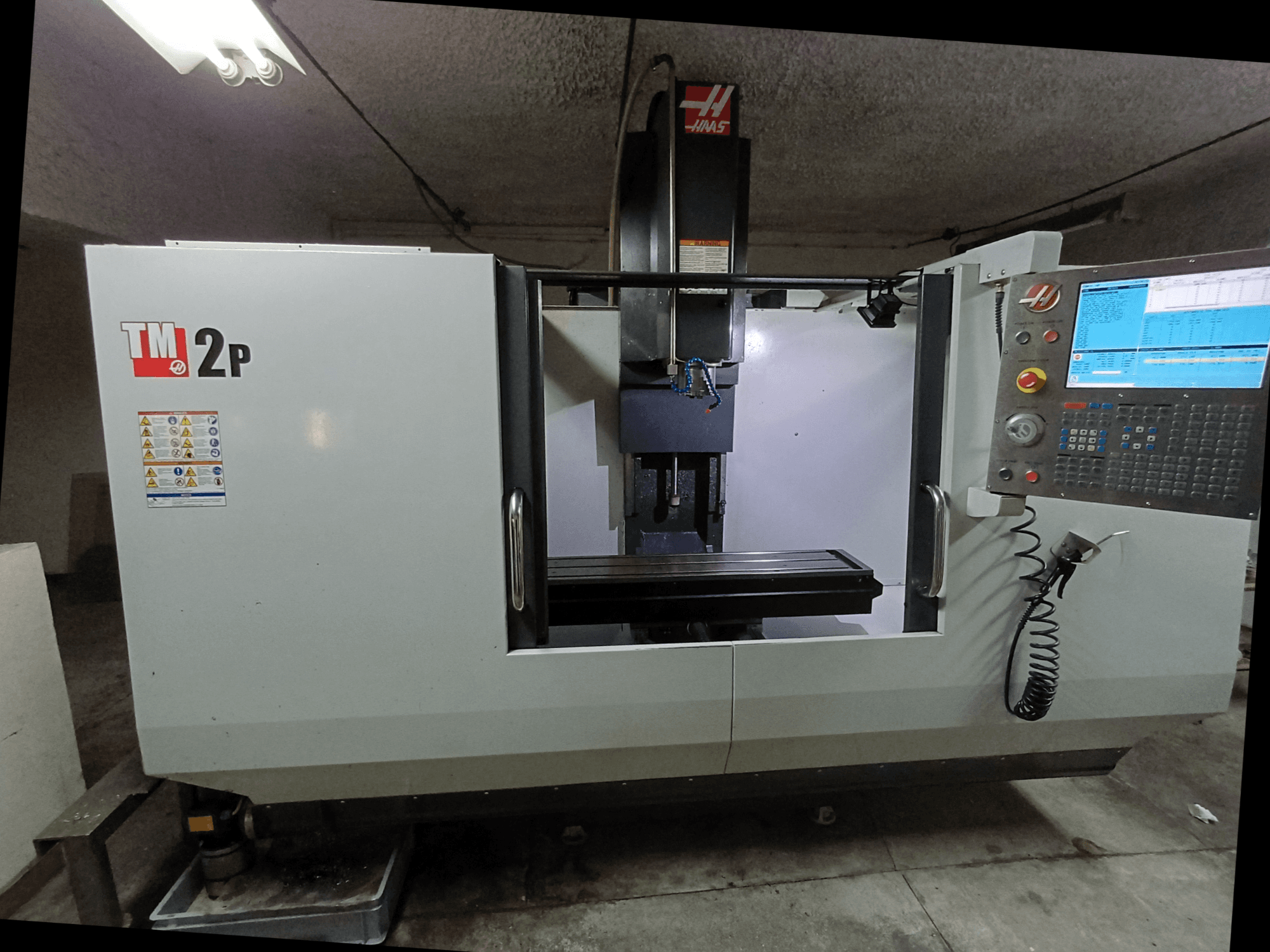 HAAS TM-2P vertikaalne töötlemiskeskus, esiplaan, kus on näidatud juhtpaneel, spindlipea ja töölaud.