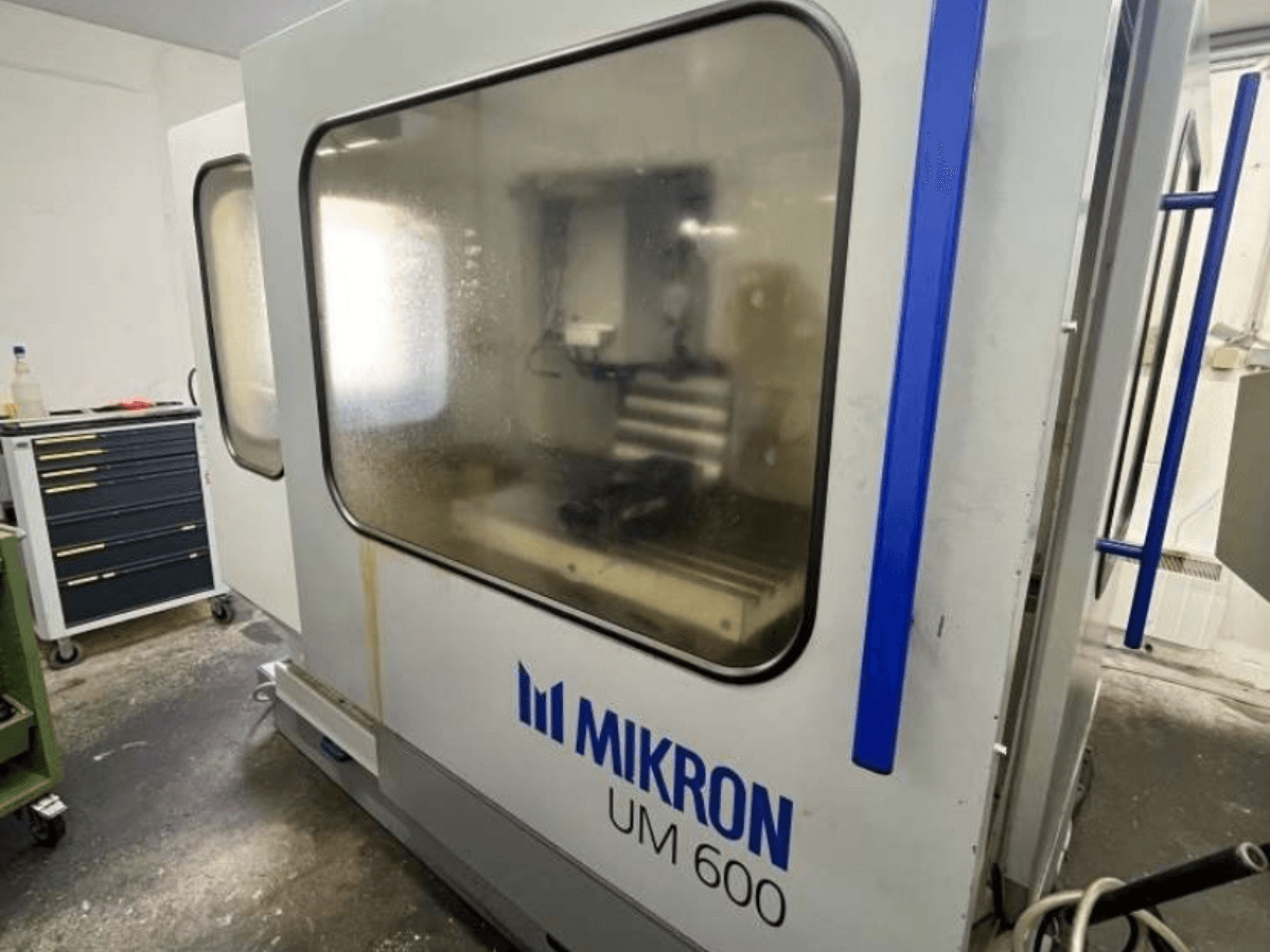 MIKRON UM 600 TNC 410/426 universaaltöötluskeskus, külgvaade, udustatud klaasiga ja nähtava tööriistahoidla lähedal.