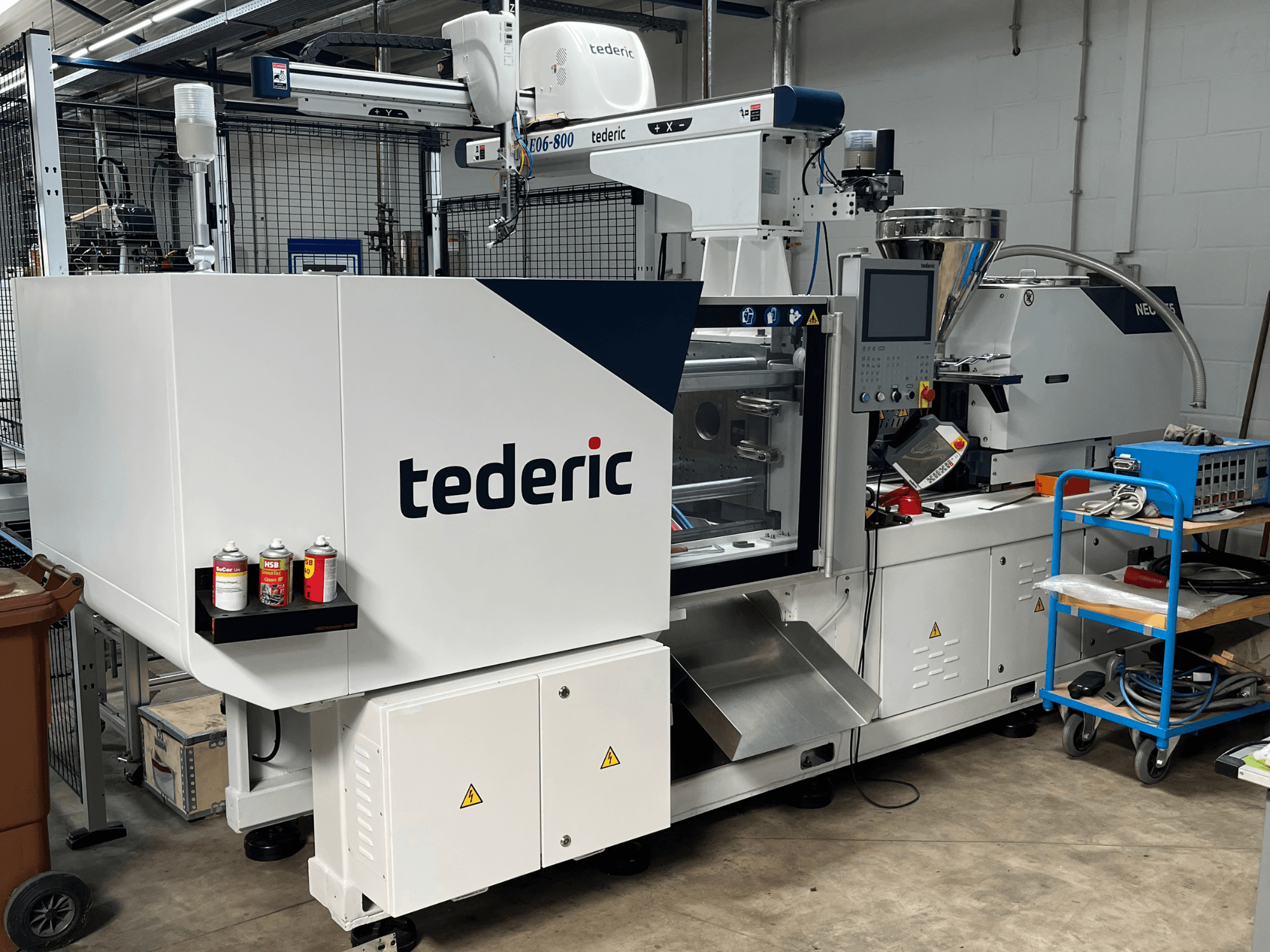 Hüdrauliline survevalumasin TEDERIC NEO.E55/e110h töökodas, külgvaade koos juhtpaneeli ja kõrval asuvate tööriistadega.