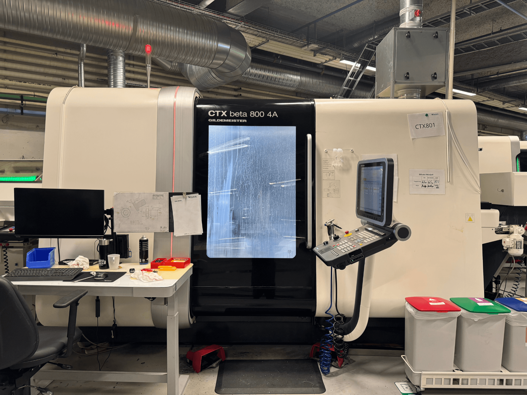 CTX beta 800 4A masin koos juhtpaneeli ja monitoriga, külgvaade, töökojas koos kontori ja värviliste prügikastidega.