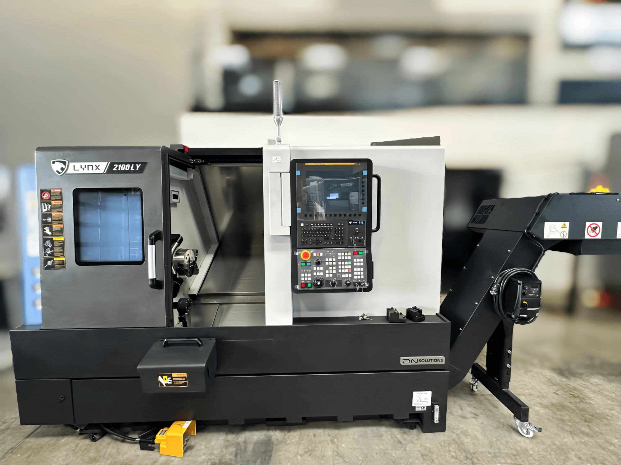 Horisontaalne treipink DN SOLUTIONS LYNX 2100LYB, esivaade, kus on juhtpaneel ja avatud uks, mis avab sisemuse.