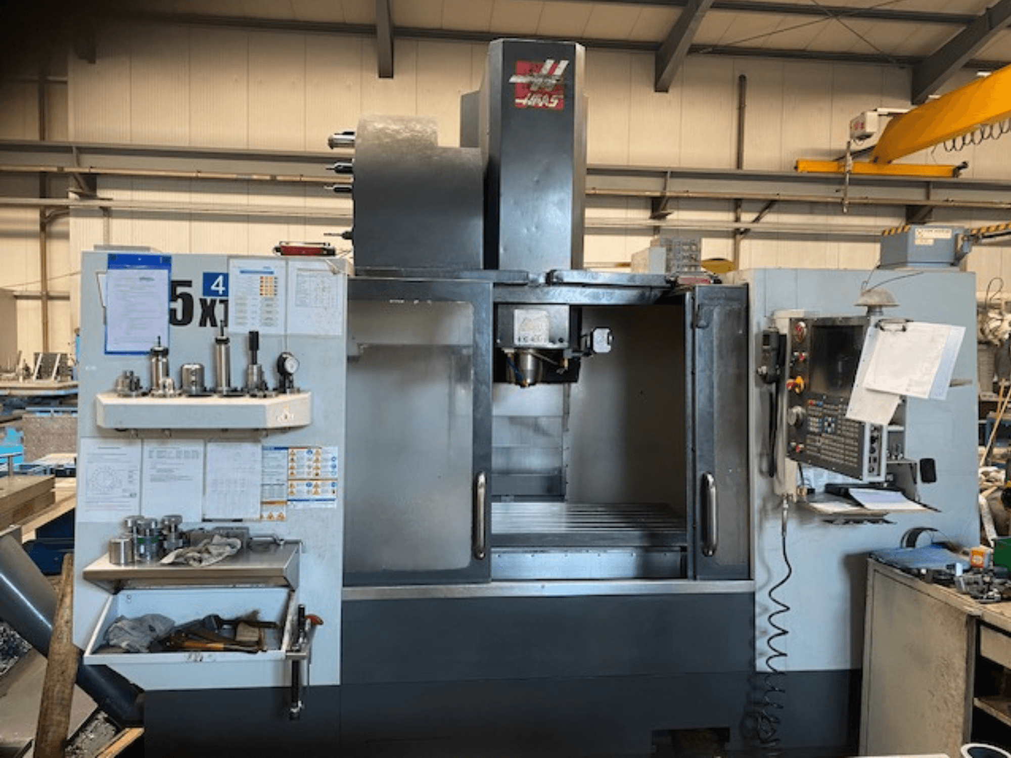 Haas VF-5 vertikaalne töötluskeskus, esivaade, kus on näha juhtpaneel, tööriistade hoidla ja spindli ala.
