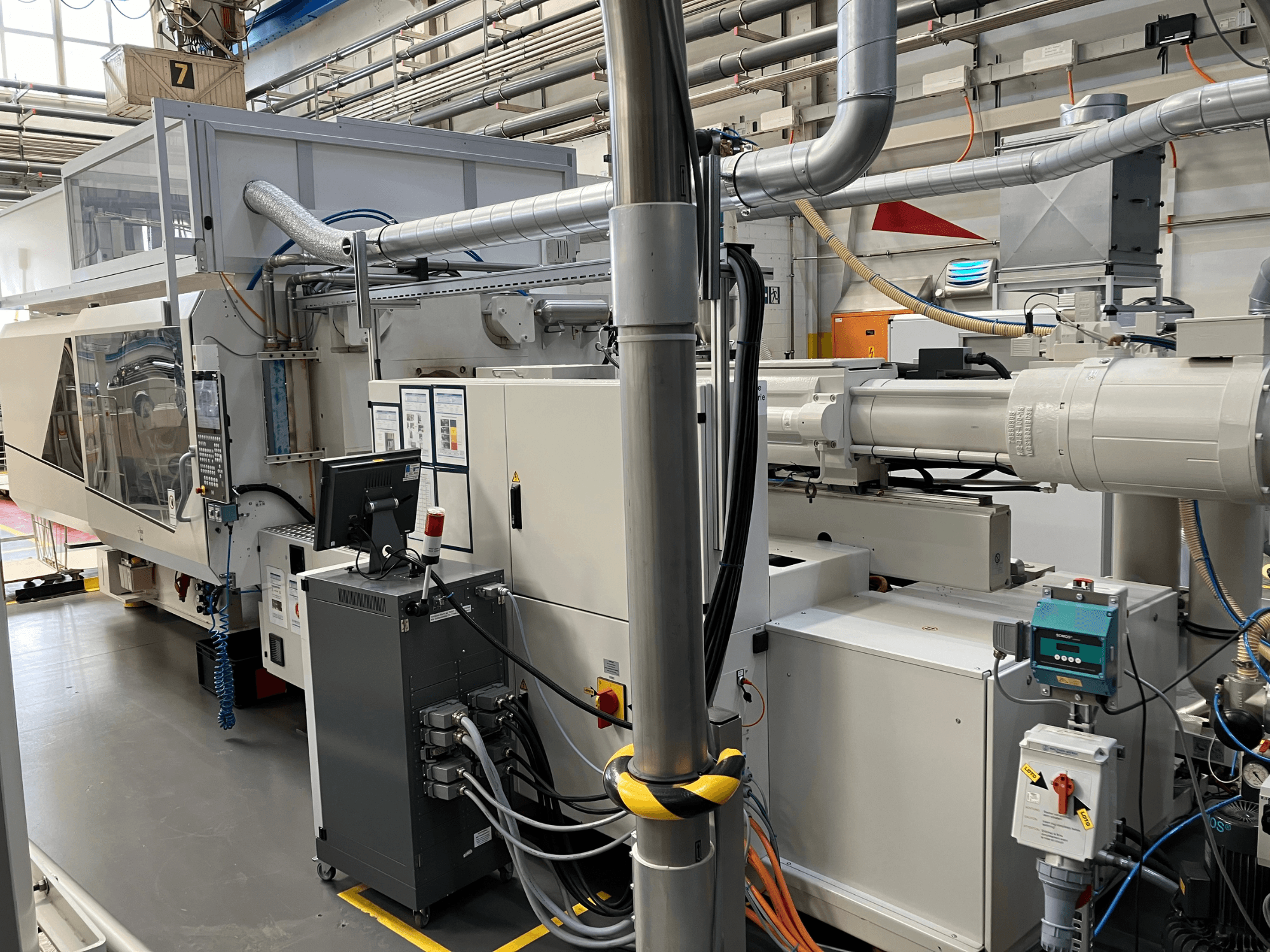 Tööstusmasinad juhtpaneeliga, esiplaanil, millel on torud, elektrilised komponendid ja turvaelemendid.