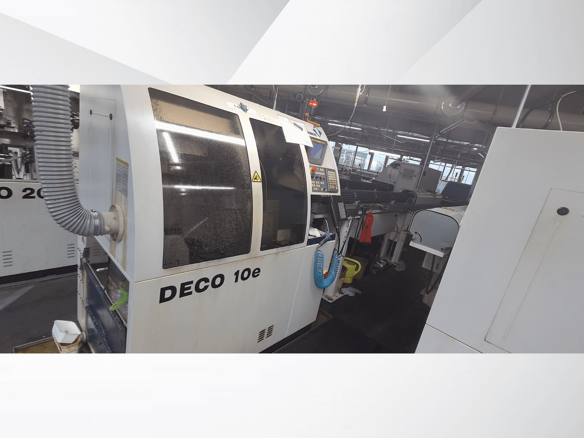 DECO 10e masin töökojas; külgvaates on näha juhtpaneel ja ventilatsioonivoolik, taustal ähmased masinad.