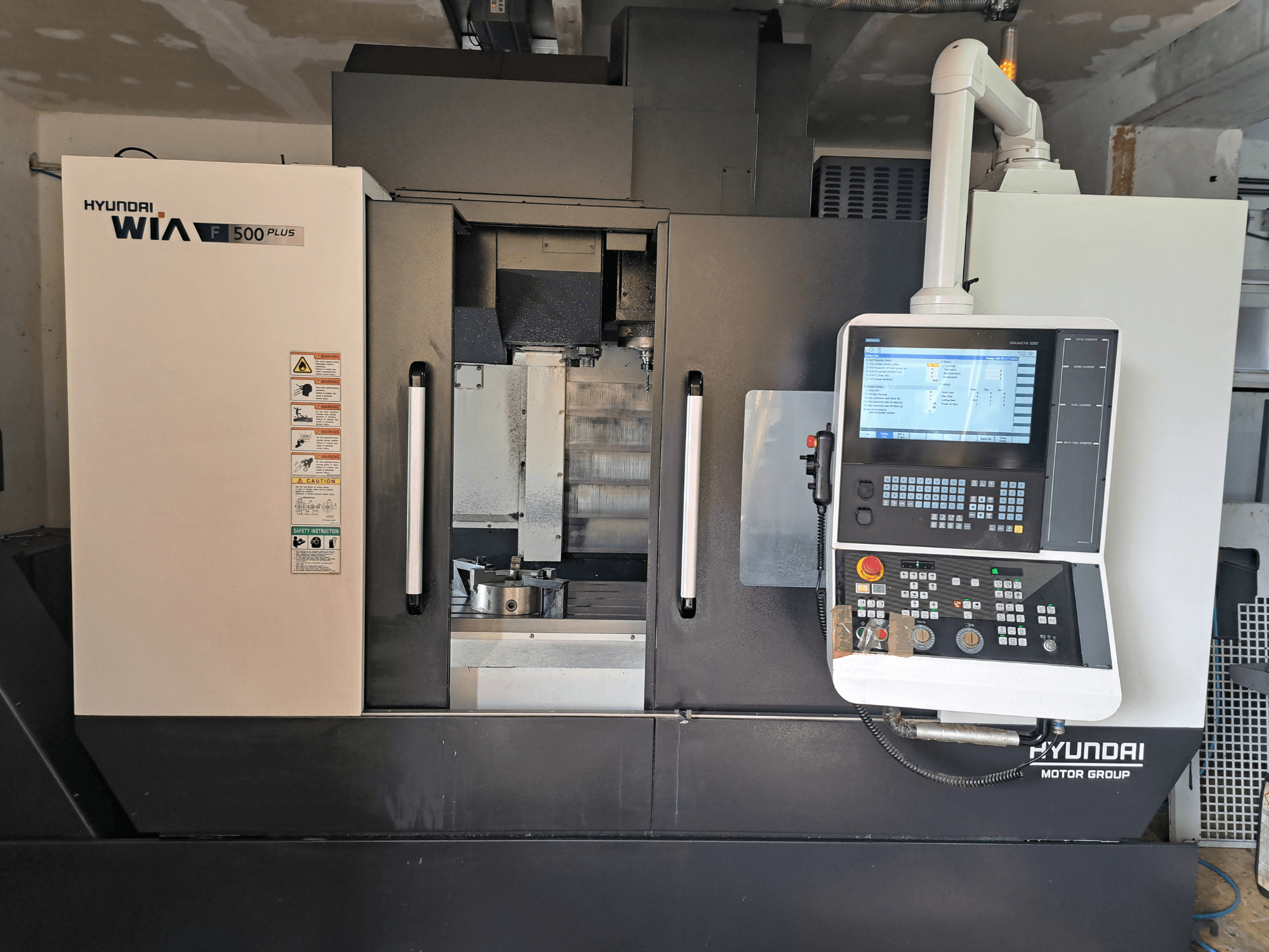 Hyundai WIA F500 Plus CNC-tööpink eesvaates, millel on digitaalne juhtpaneel ja ohutussildid.