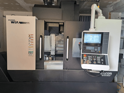 Hyundai WIA F500 Plus CNC-tööpink eesvaates, millel on digitaalne juhtpaneel ja ohutussildid.