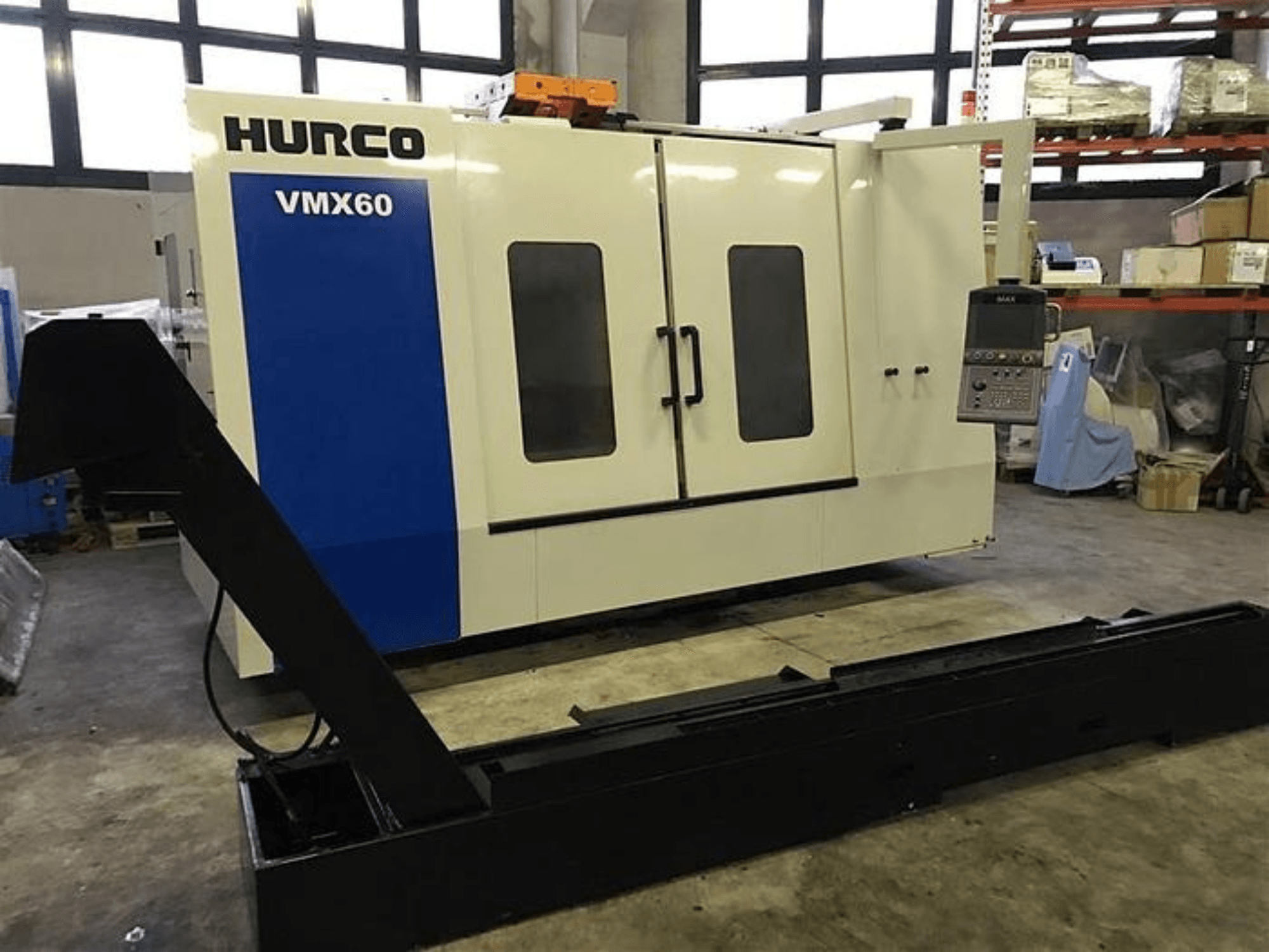 HURCO VMX60 CNC-tööpink töökojas, esivaade, millel on juhtpaneel ja kinnitatud must tugiraudtee.