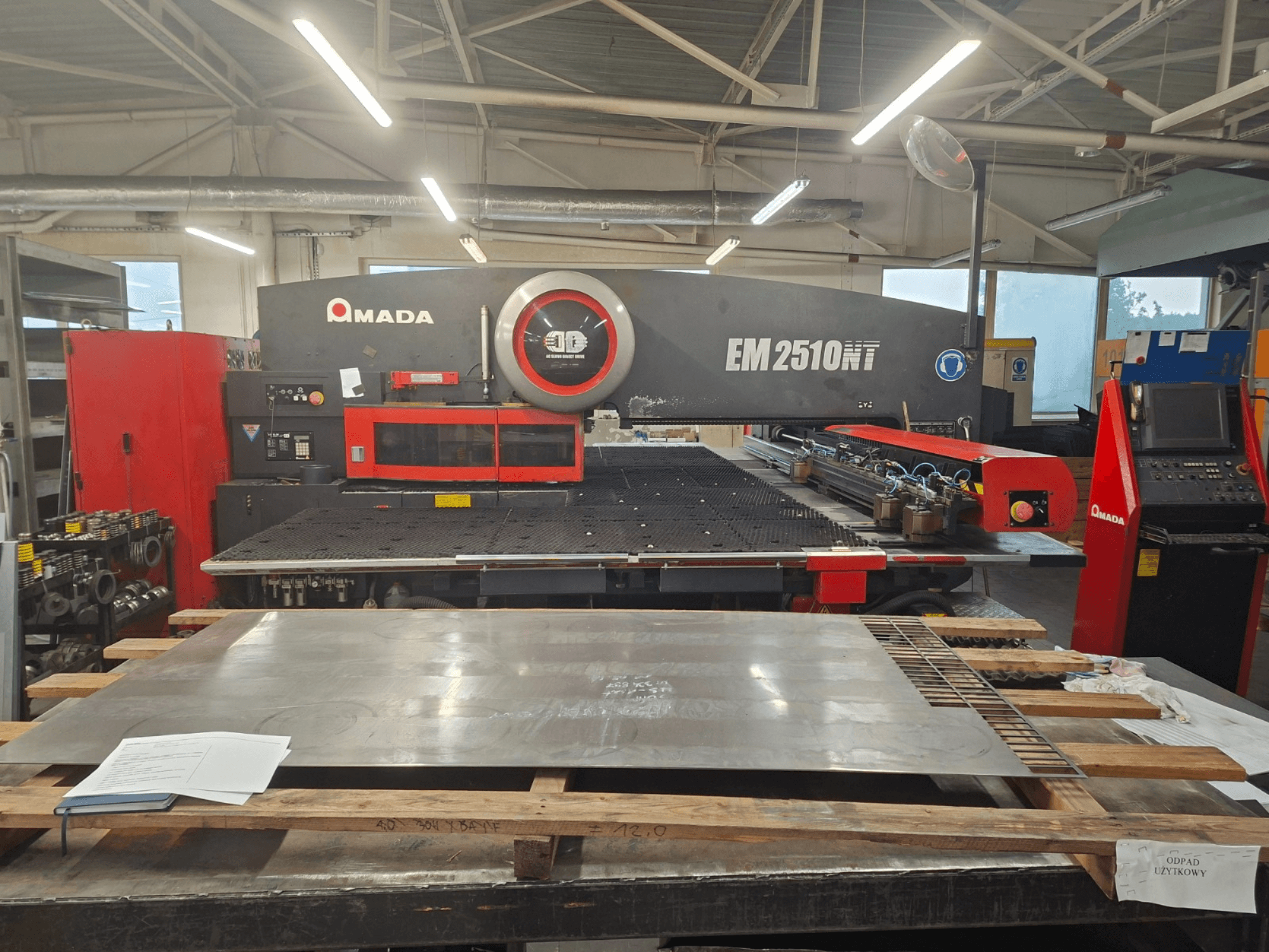 AMADA EM 2510NT revolvritoruga stantsimispressi esivaade, kus on näha metallplaat ja juhtpaneel töökojas.