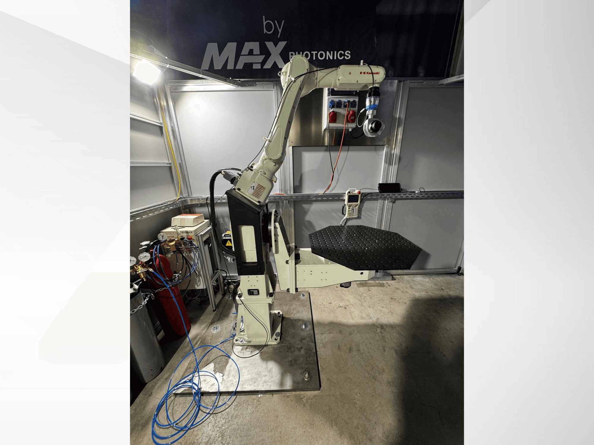 Max Photonics robotkäe seade, esiplaanil, millel on must perforeeritud platvorm ja juhtpaneel koos mõõteriistade ja kaablitega.