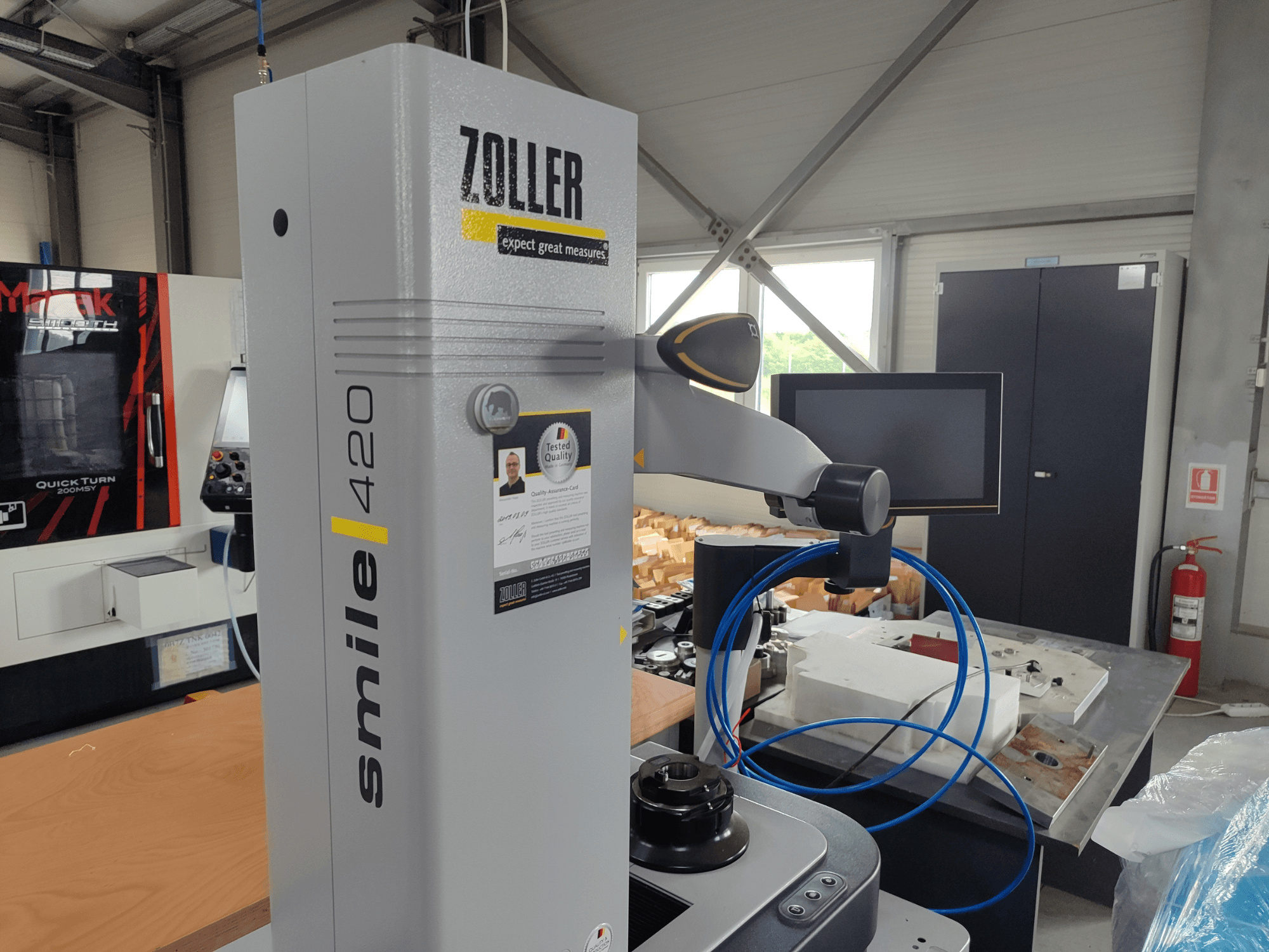 ZOLLER smile 420 mõõteseade koos monitoriga, külgvaade töökojas, taustal sinised voolikud ja masinad.