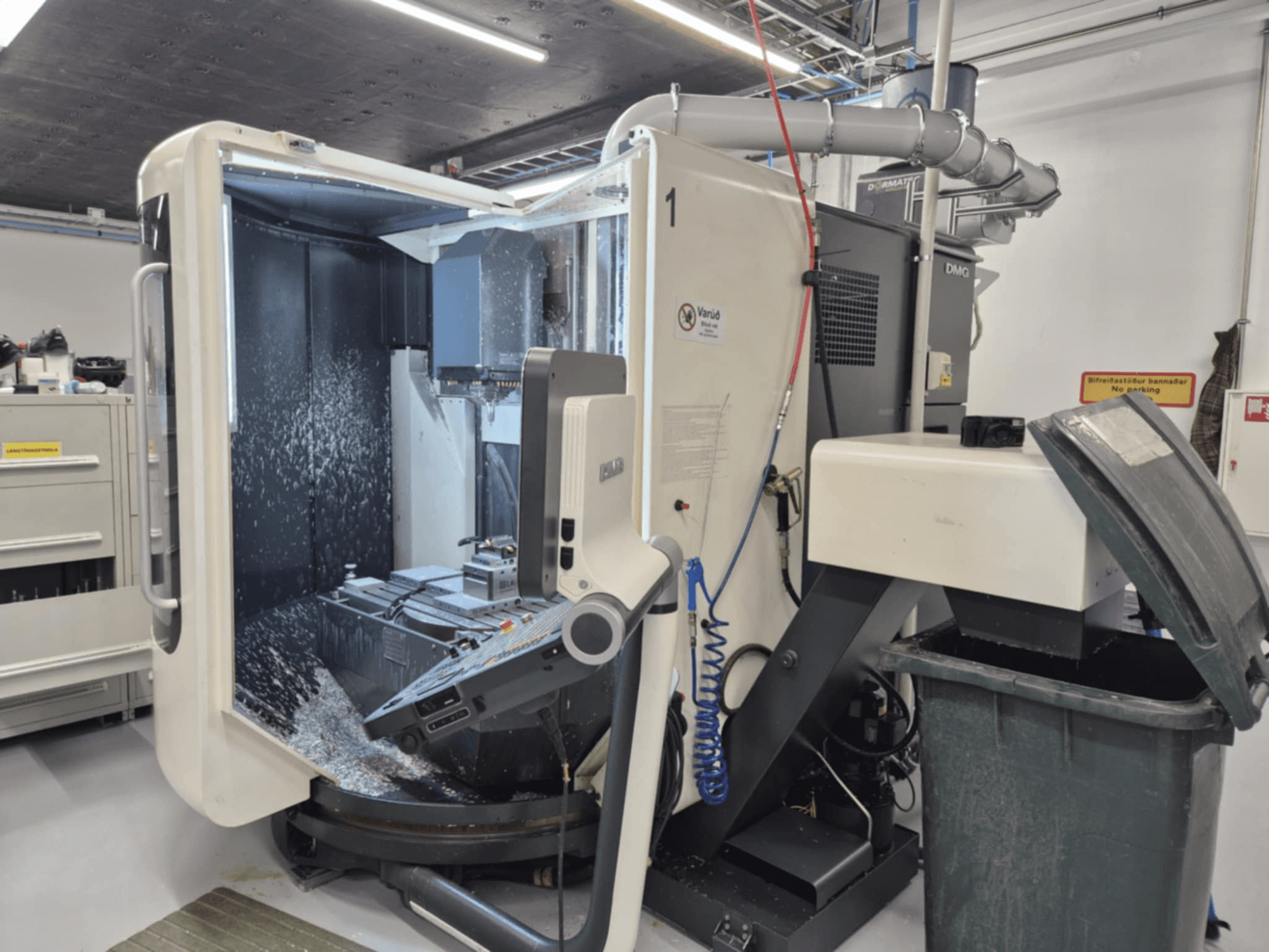 Avatud DMG freespink jahutusvedeliku pihustusega, millel on metallilaastud ja tööriista juhtimisseadmed, vaadatuna eestpoolt.