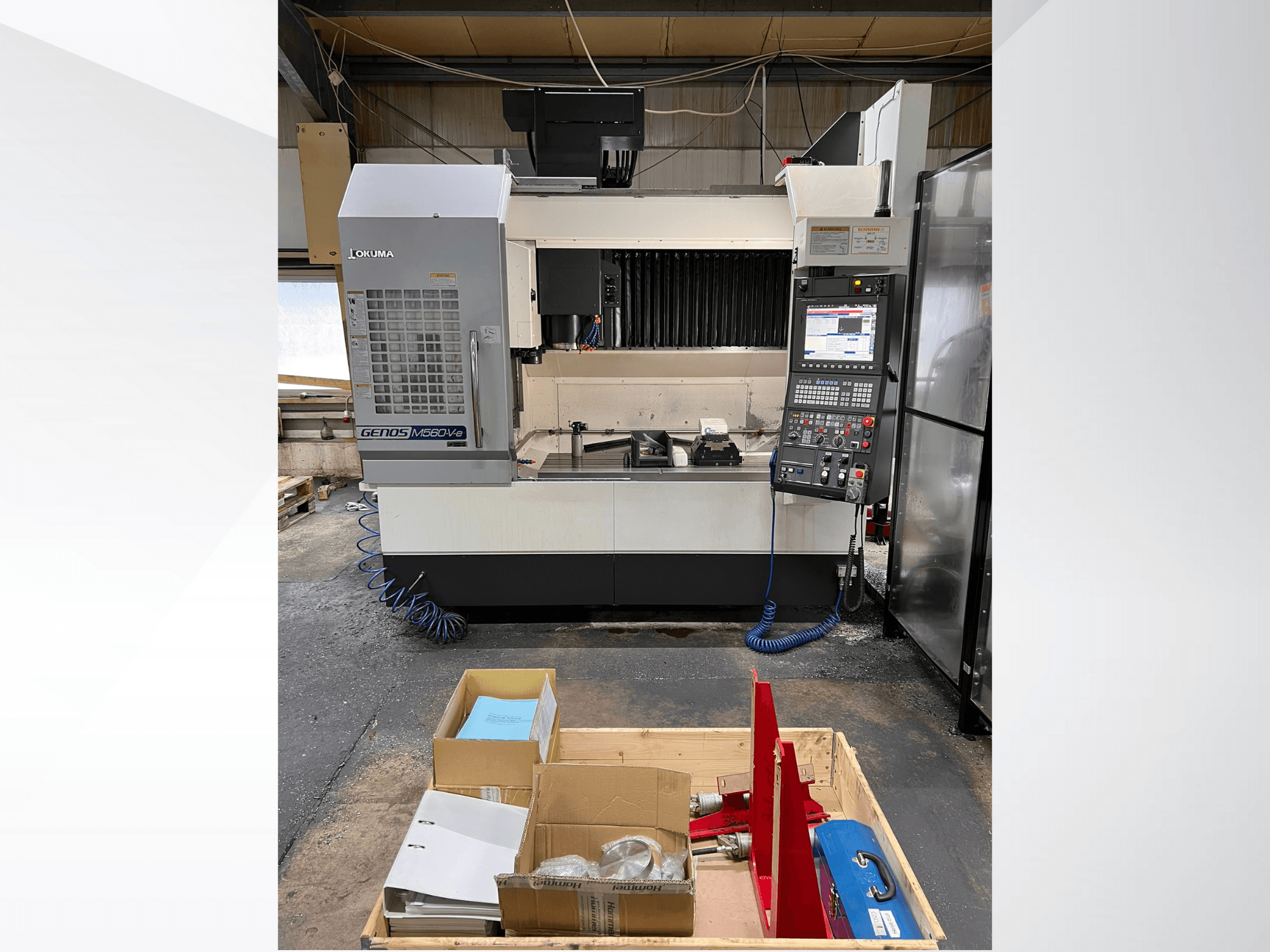 Okuma GENOS M460V-5 vertikaalne töötlemiskeskus, esiplaan, juhtpaneel nähtav ja tööriistad töölaual.