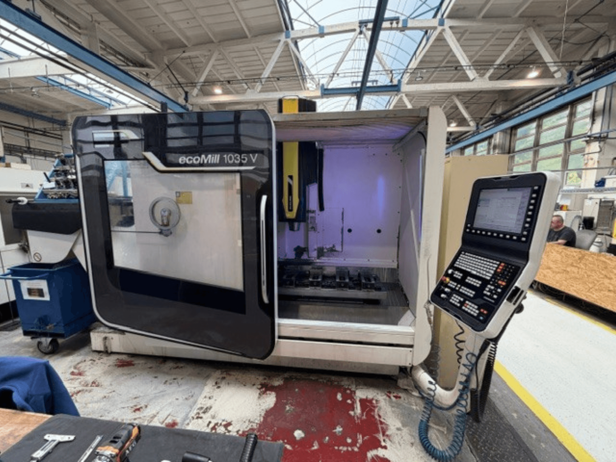 DMG MORI ecoMill 1035V vertikaalse töötlemiskeskuse esivaade avatud uksega, millel on näha juhtpaneel ja töötsoon seadme sees.