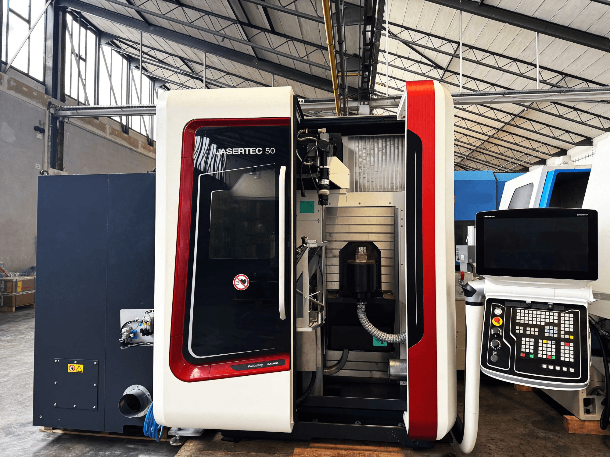 LaserTec 50 CNC-tööpingi külgvaade, millel on mustvalge juhtpaneel, nähtav tööriistahoidja ja tööstuslik seadistus.