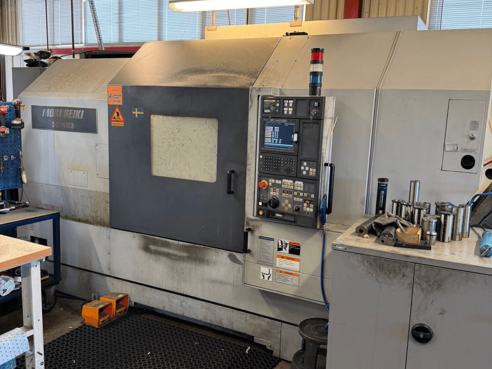MORI SEIKI SL-403BMC/800 horisontaalne treipink töökojas, näidatakse juhtpaneeli ja lähedal asuvaid tööriistu, külgvaade.