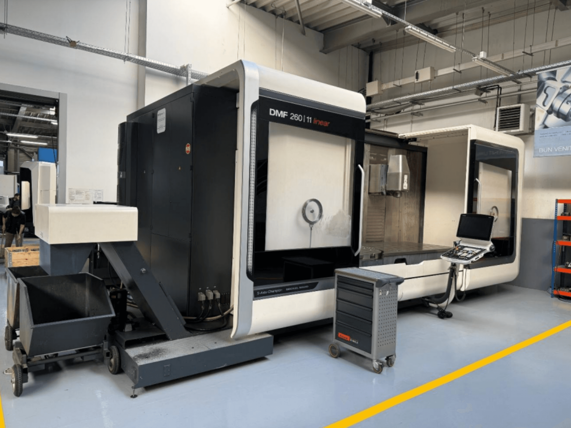 DMG MORI DMF 260 lineaarfreespingi esiplaanil, tööriistade juhtpaneel ja teisaldatav tööriistakäru lähedal.